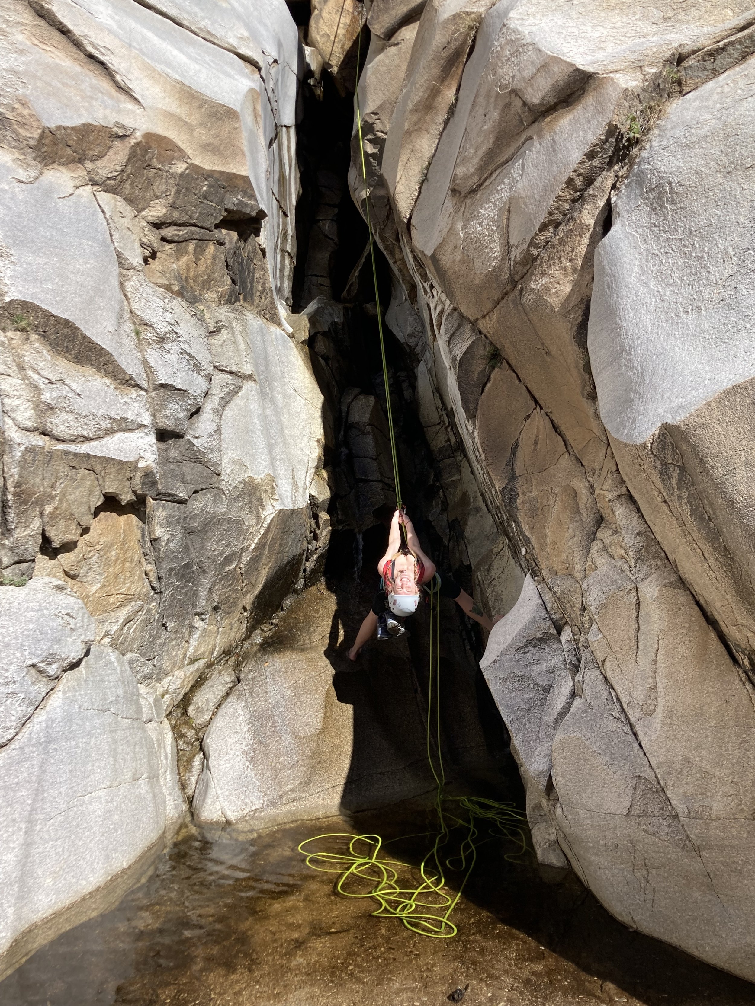 Girl rappelling upside down by waterfall