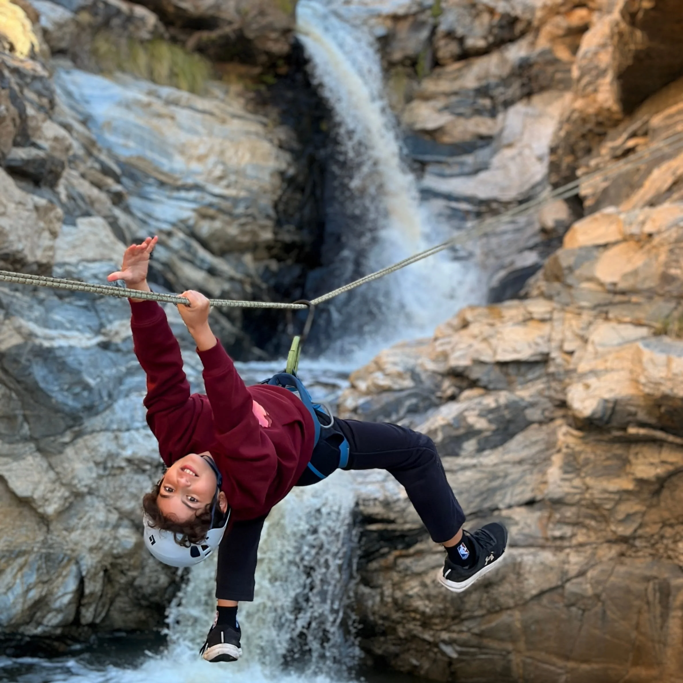 Canyoneer crossing a Tyrolean traverse above a waterfall in Tanque Verde Canyon near Tucson