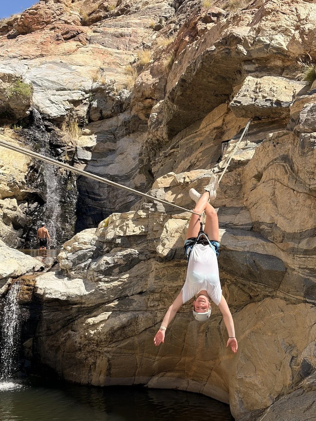 Guest crossing a Tyrolean traverse during a guided canyoneering trip in Tanque Verde Canyon