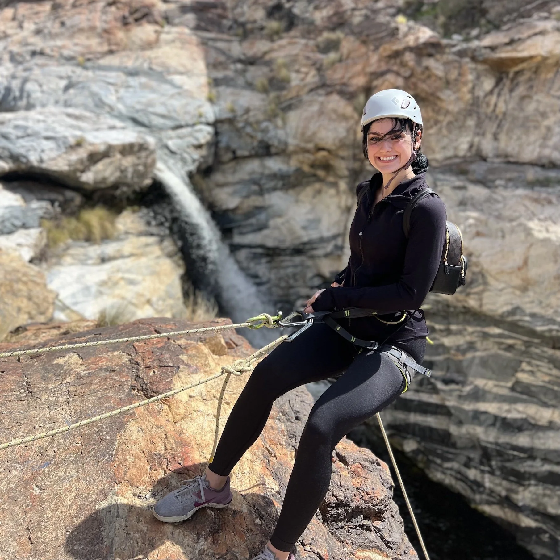 Canyoneer preparing to rappel beside a waterfall in Tanque Verde Canyon.