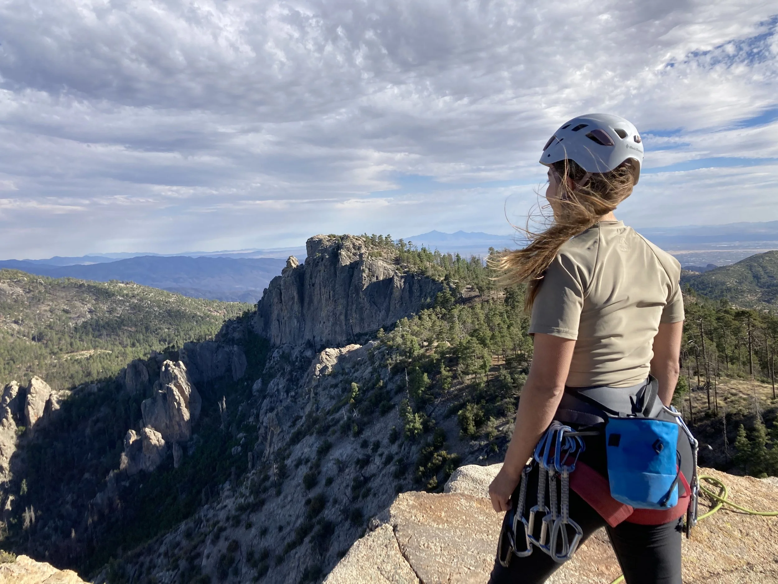Girl in climbing gear overlooking rock cliffs
