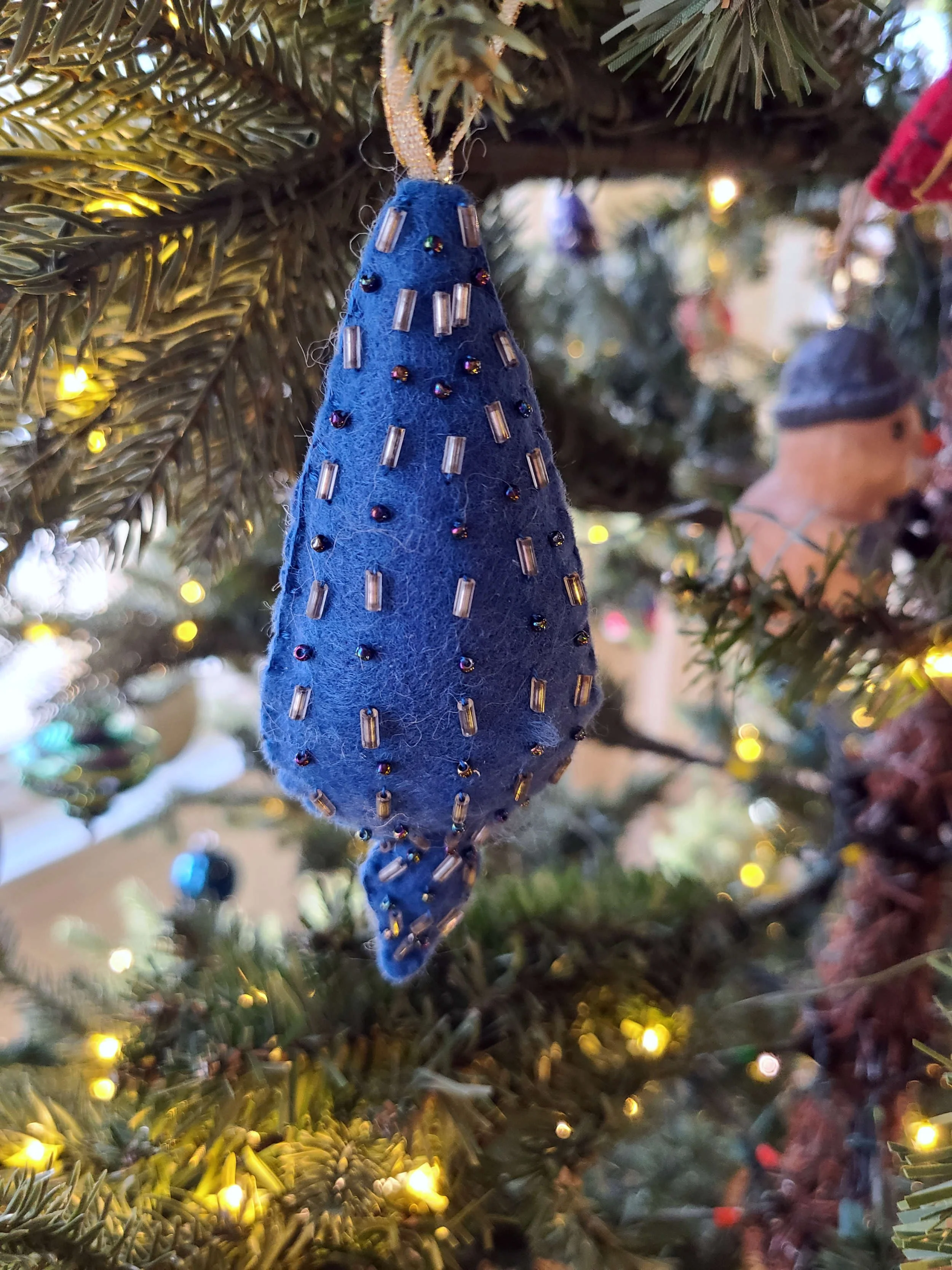 photo of a blue felt ornament in a traditional teardrop ornament shape, embroidered with silver and blue beads.