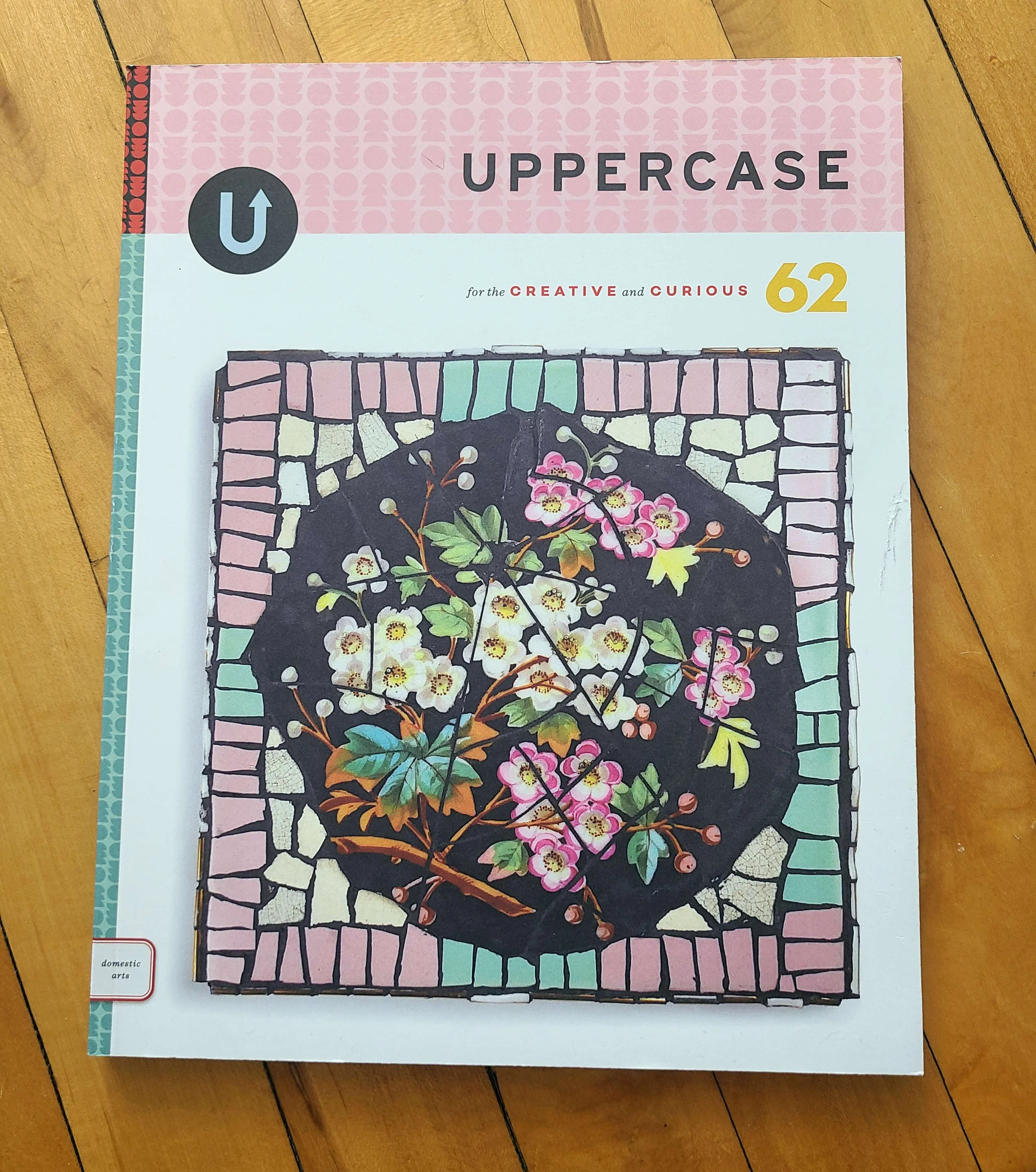 Photo of a magazine on a wood floor. The magazine is titled UPPERCASE 62 and has a subtitle "for the creative and curious."