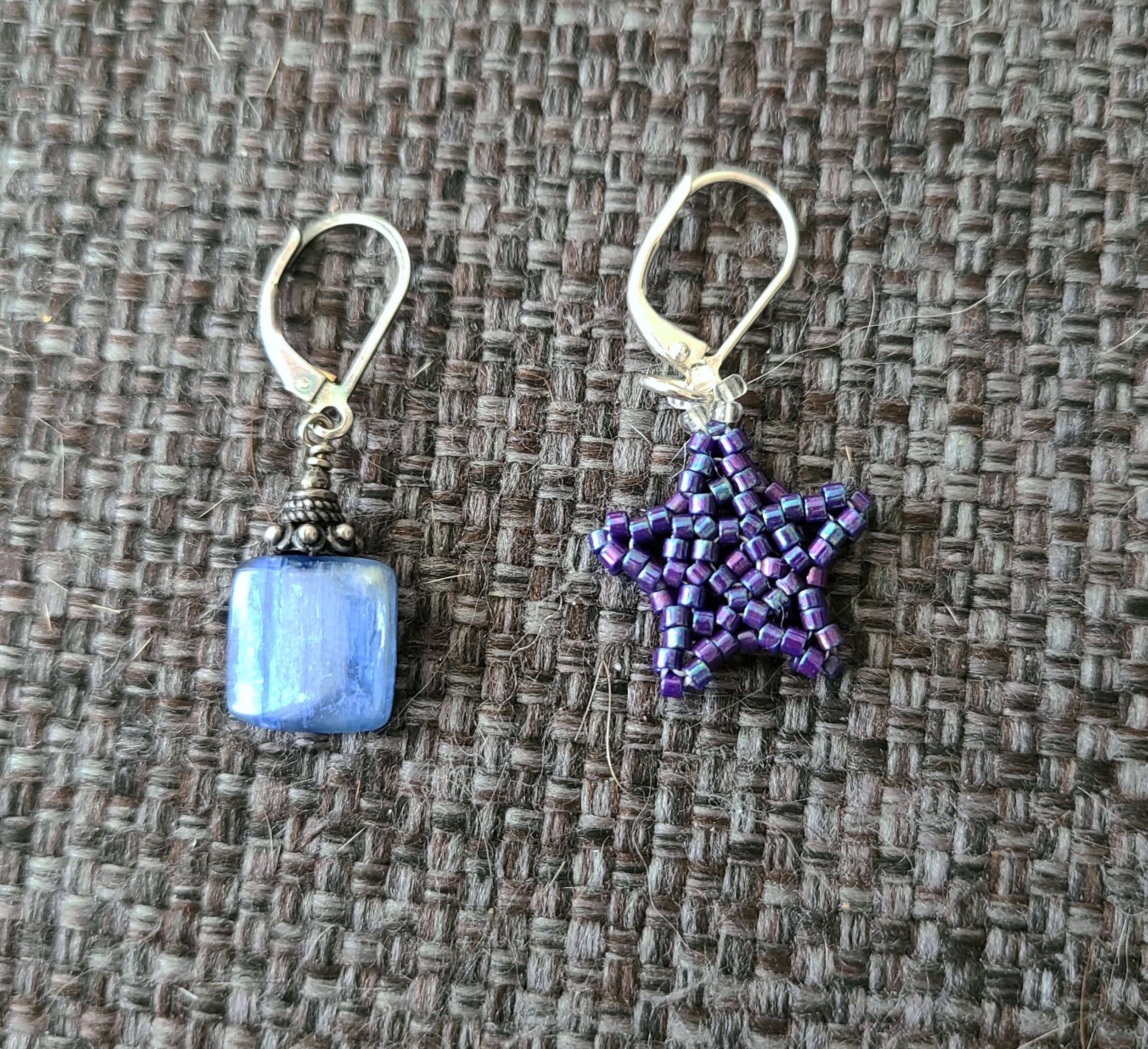 photo of two small earrings and/or stitch markers with loop earring clasps on a gray background. The closures are exactly the same.