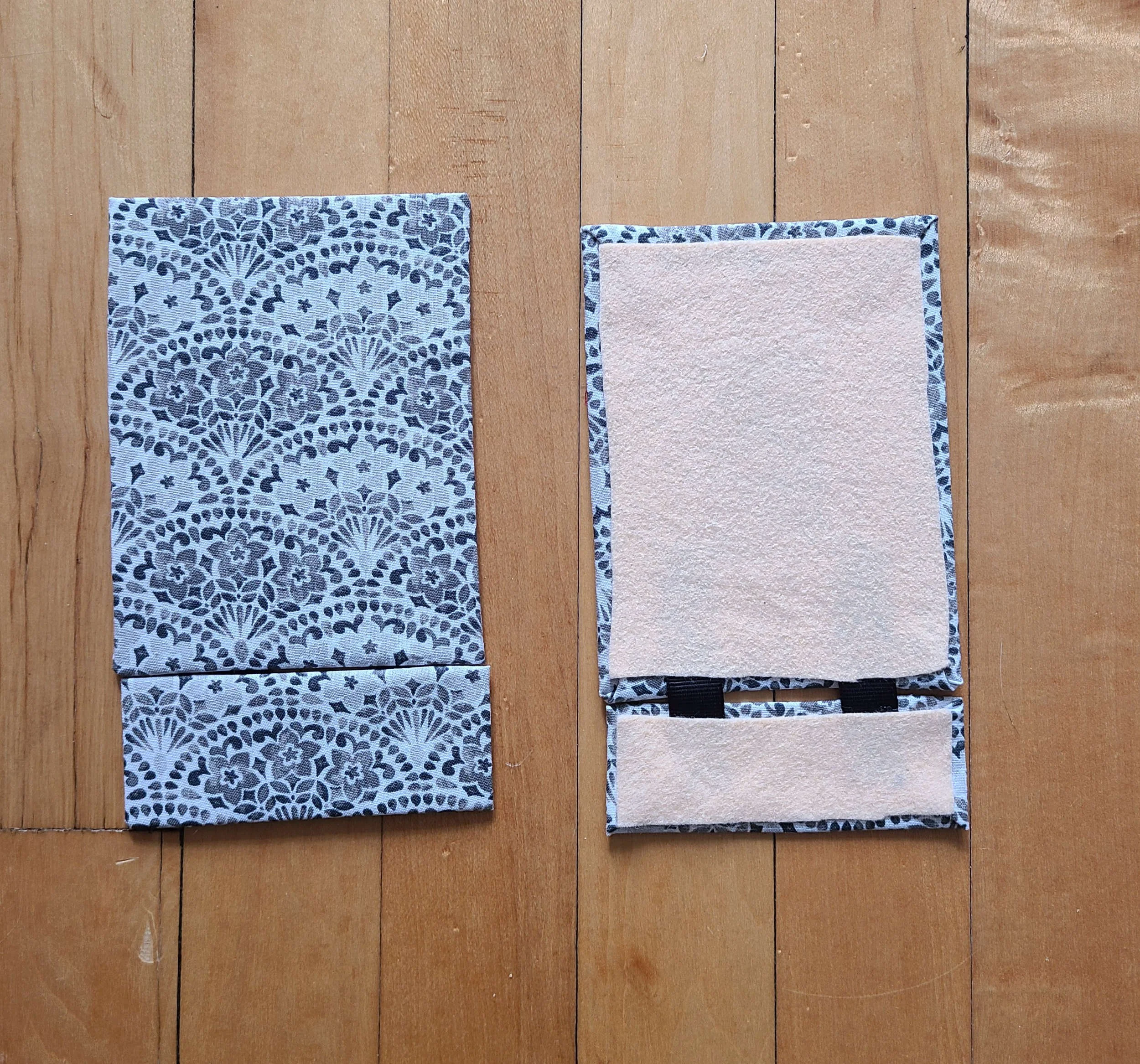 photo of two fabric covered rectangles. The left one is front facing and shows a gray patterned fabric. The right one is rear facing and has a square of peach felt taped to the back, and a black ribbon connecting it to a smaller rectangle.