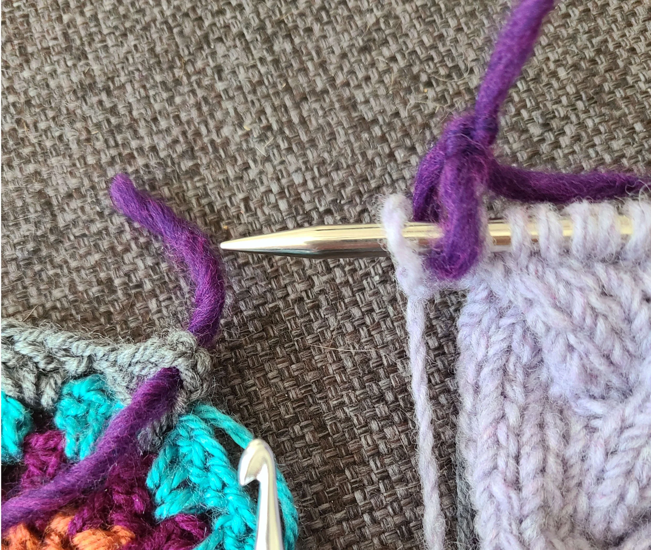 image of an in progress knit and in progress crochet projects, both with thick dark purple yarn serving as markers. The knit marker is tied in a ring and the crochet marker is just threaded through a stitch.