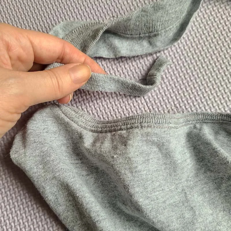 Photo of the back of a gray T-shirt, the top ribbing of the neck has been cut away but the seam where the ribbing attached to the body is still on the T-shirt.