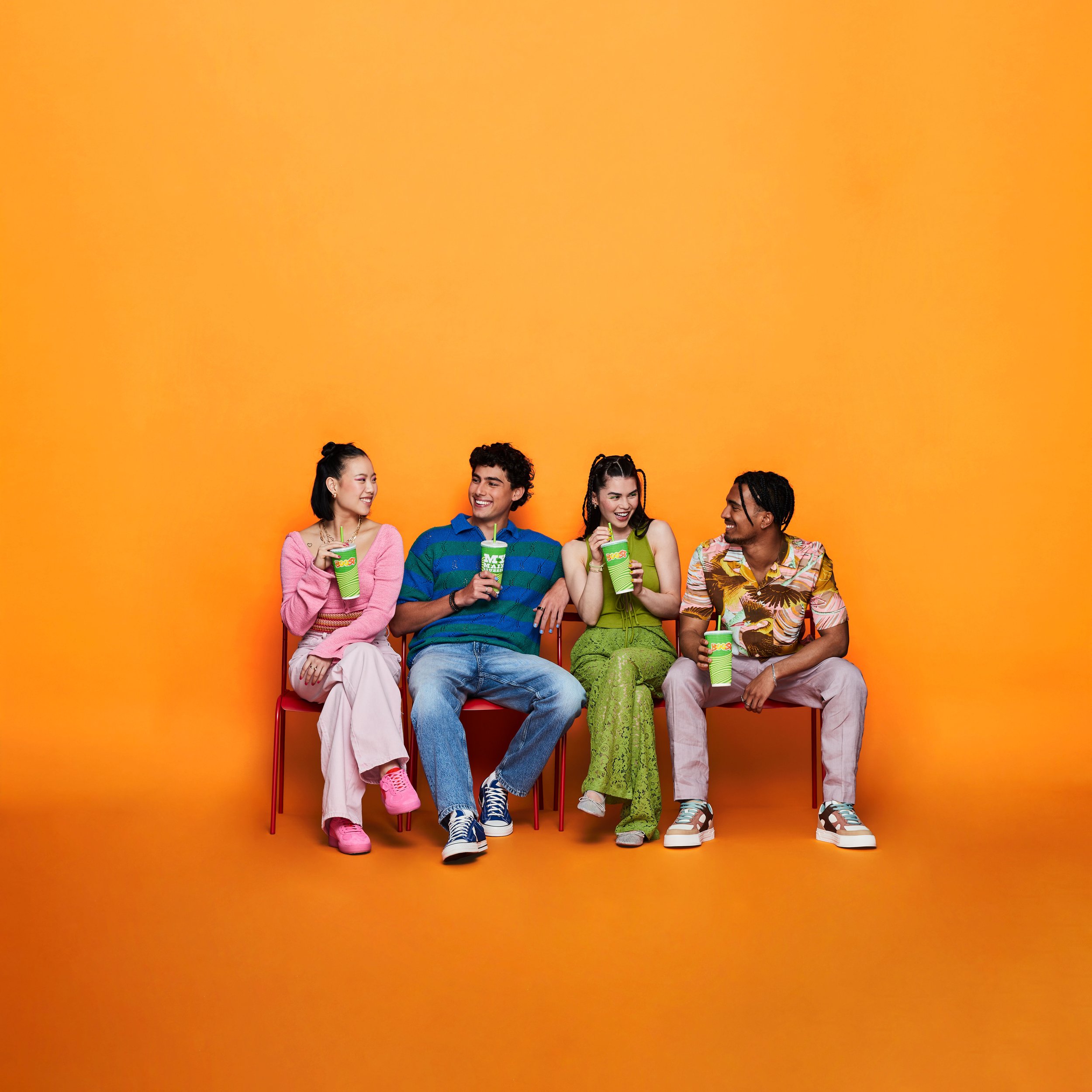 Boost_Group-sitting-on-Chairs-with-Boost-Cups_Orange-BG_1.jpg