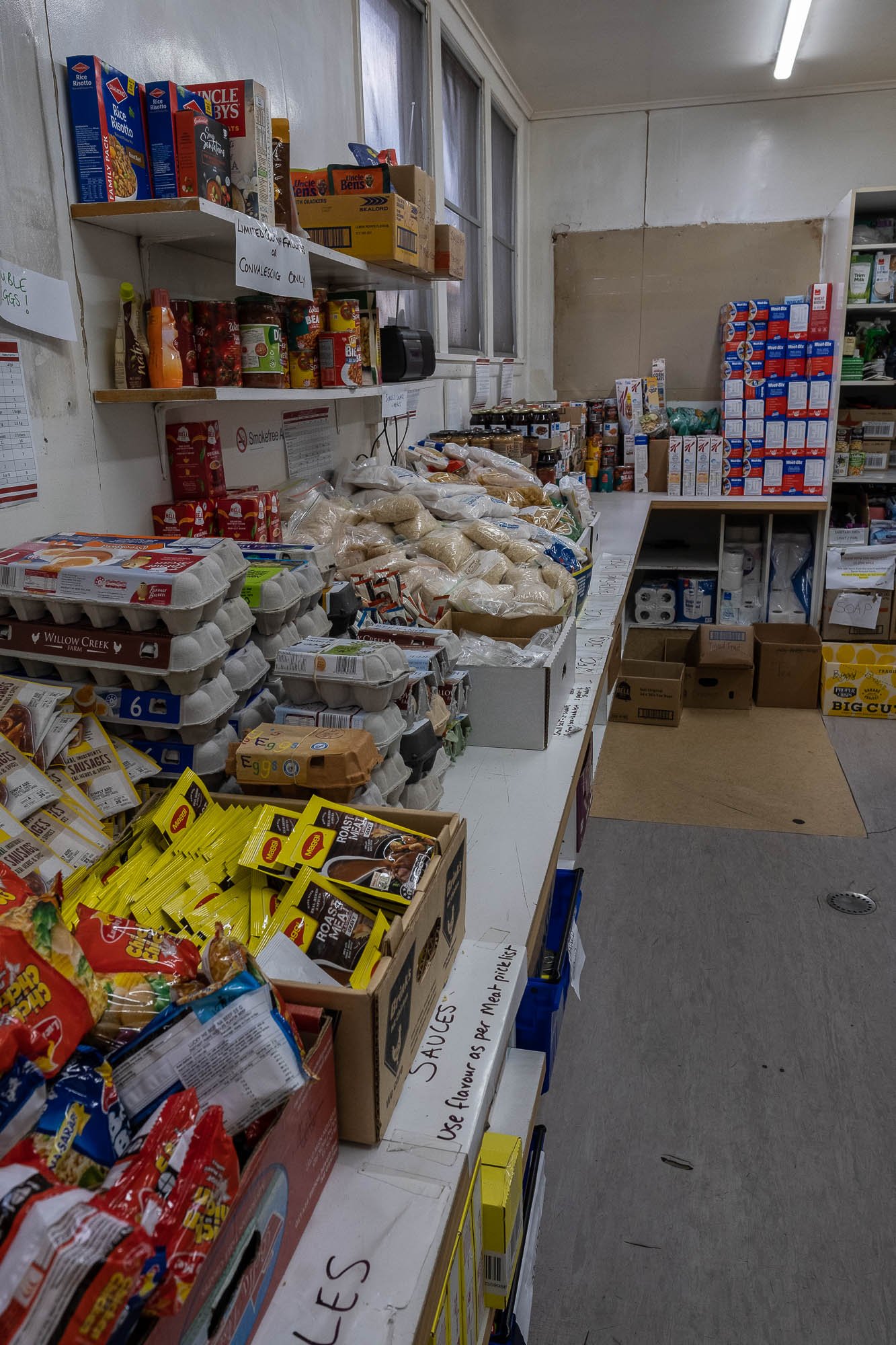 Shelf of various food items, including eggs, snacks, and canned goods, in a food pantry or grocery store.