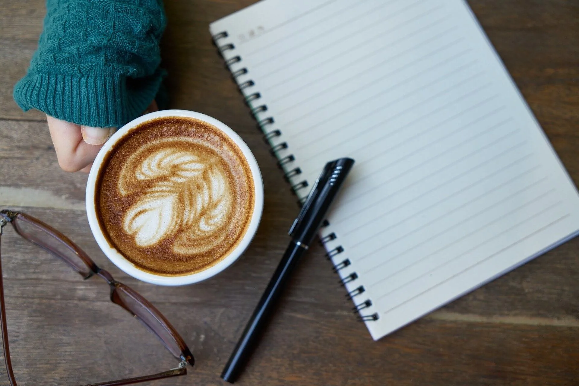 café lunettes stylo et cahier posé sur bureau routine matinale entrepreneure