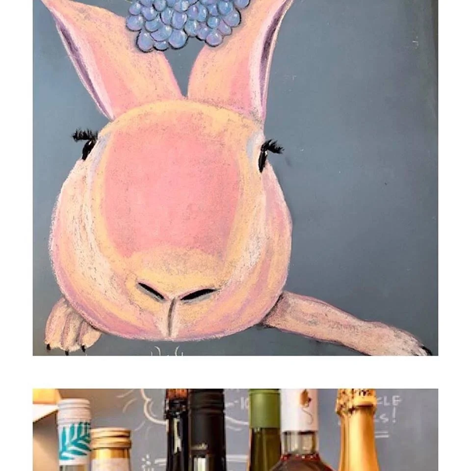 EASTER Good Wine's pink rabbit on the chalkboard wall wine bottles beneath it IMG_8870.JPG