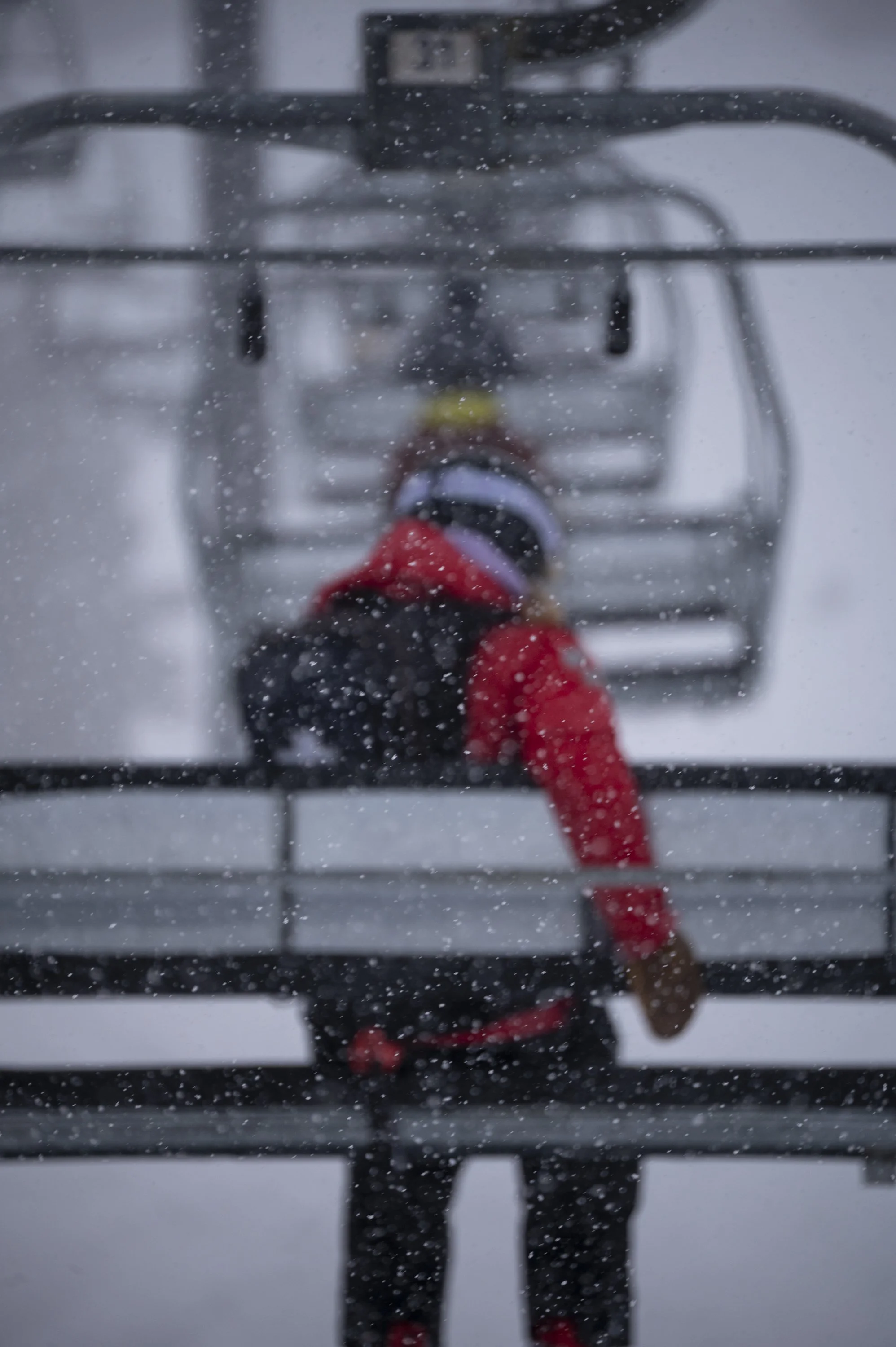 A person taking a selfie through a snow-covered mirror, with snow falling around.