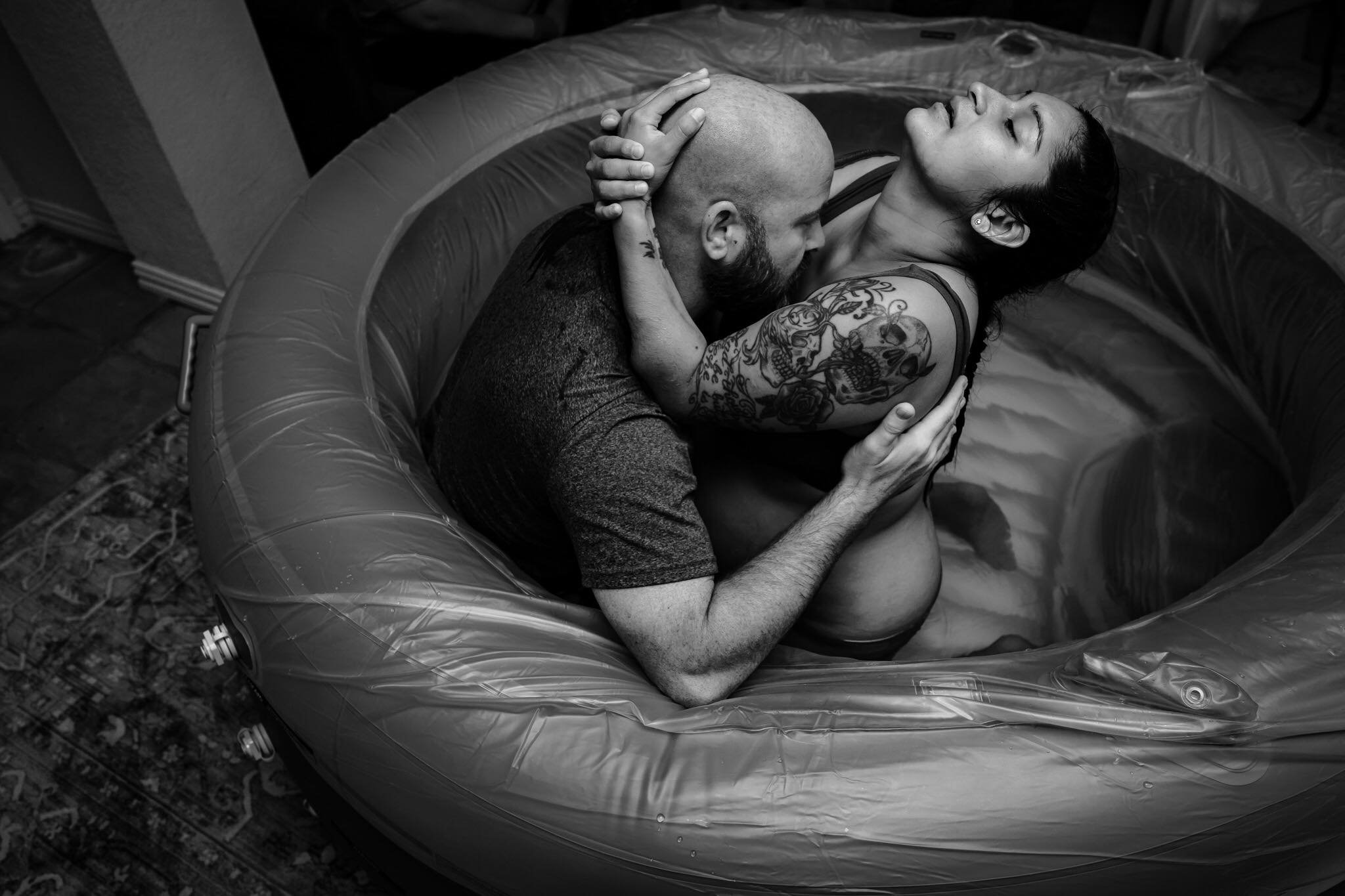 Husband embracing his wife in the birth pool as she labors during their home water birth