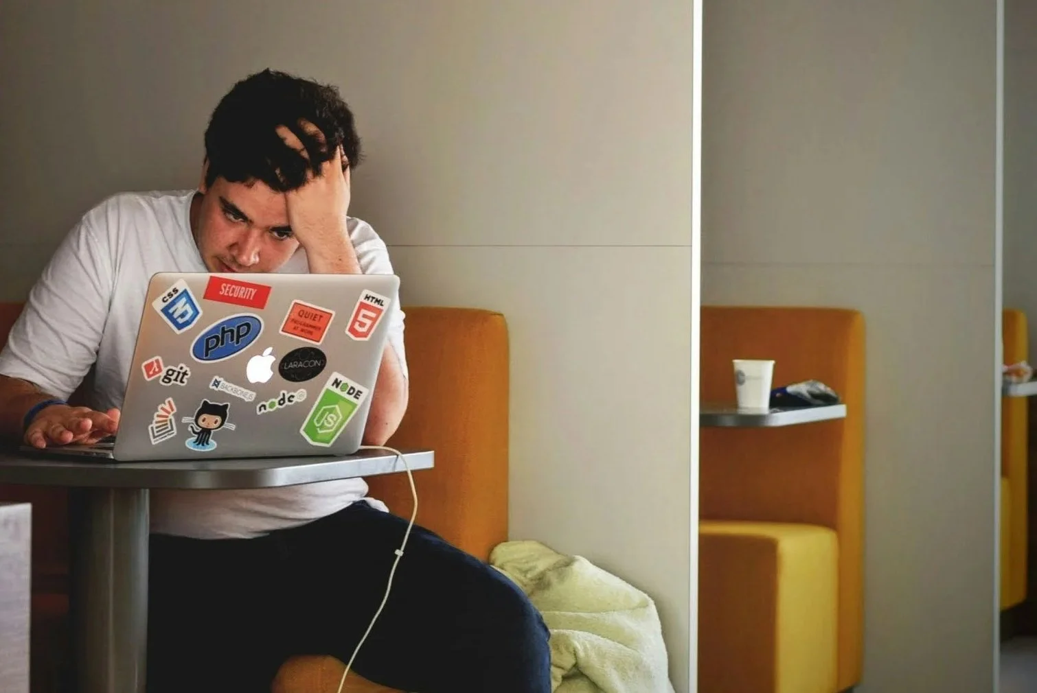 Stressed man a table with a laptop with his hand in his hair.