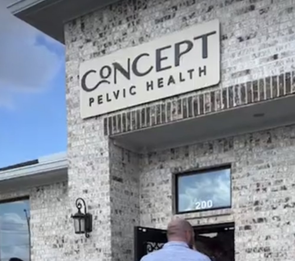 Logo design on outdoor sign above business entrance that reads 'CONCEPT Pelvic Health' on a brick building.
