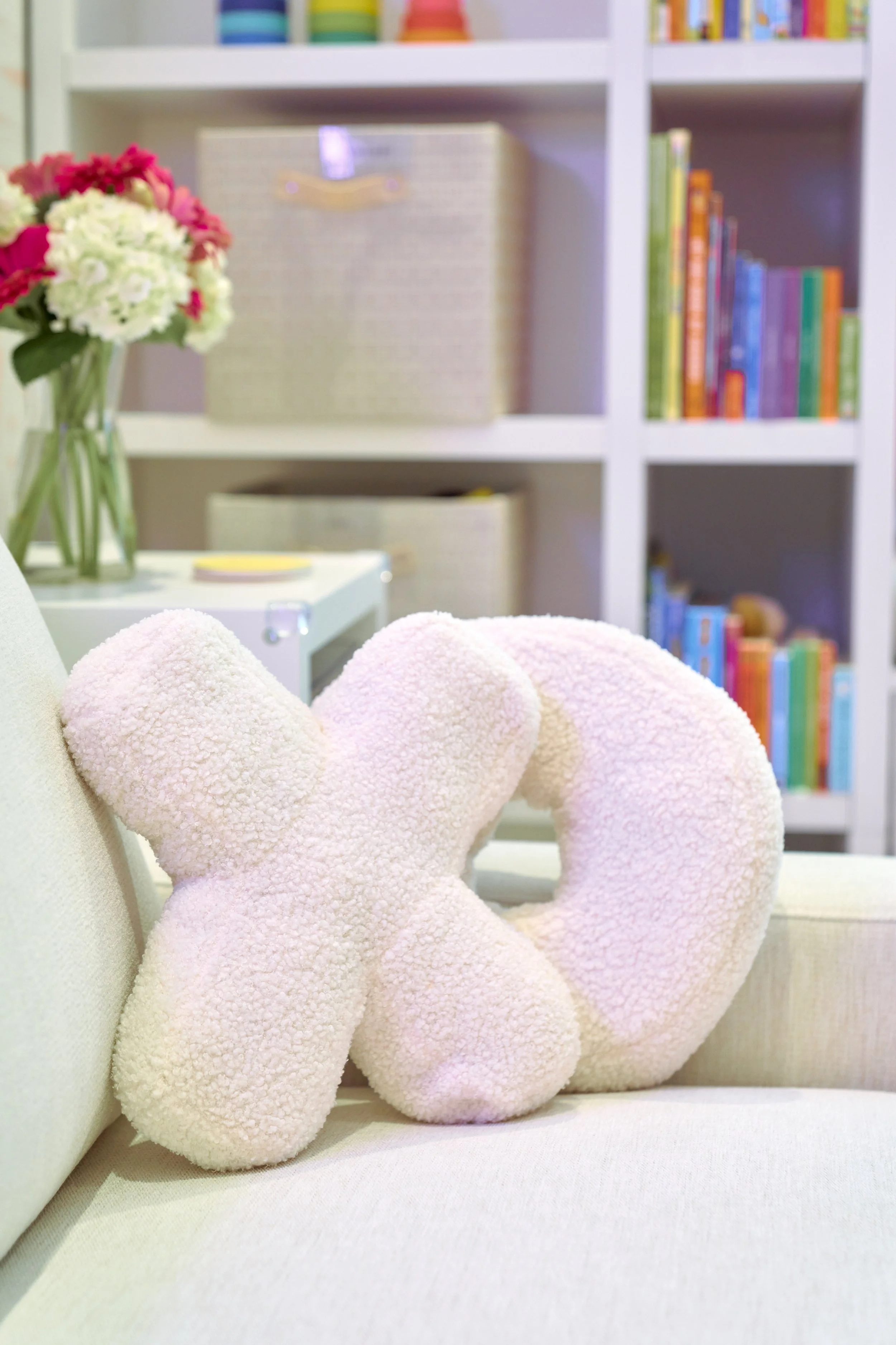 Pink plush toy shaped like a bow and a key resting on a beige sofa.