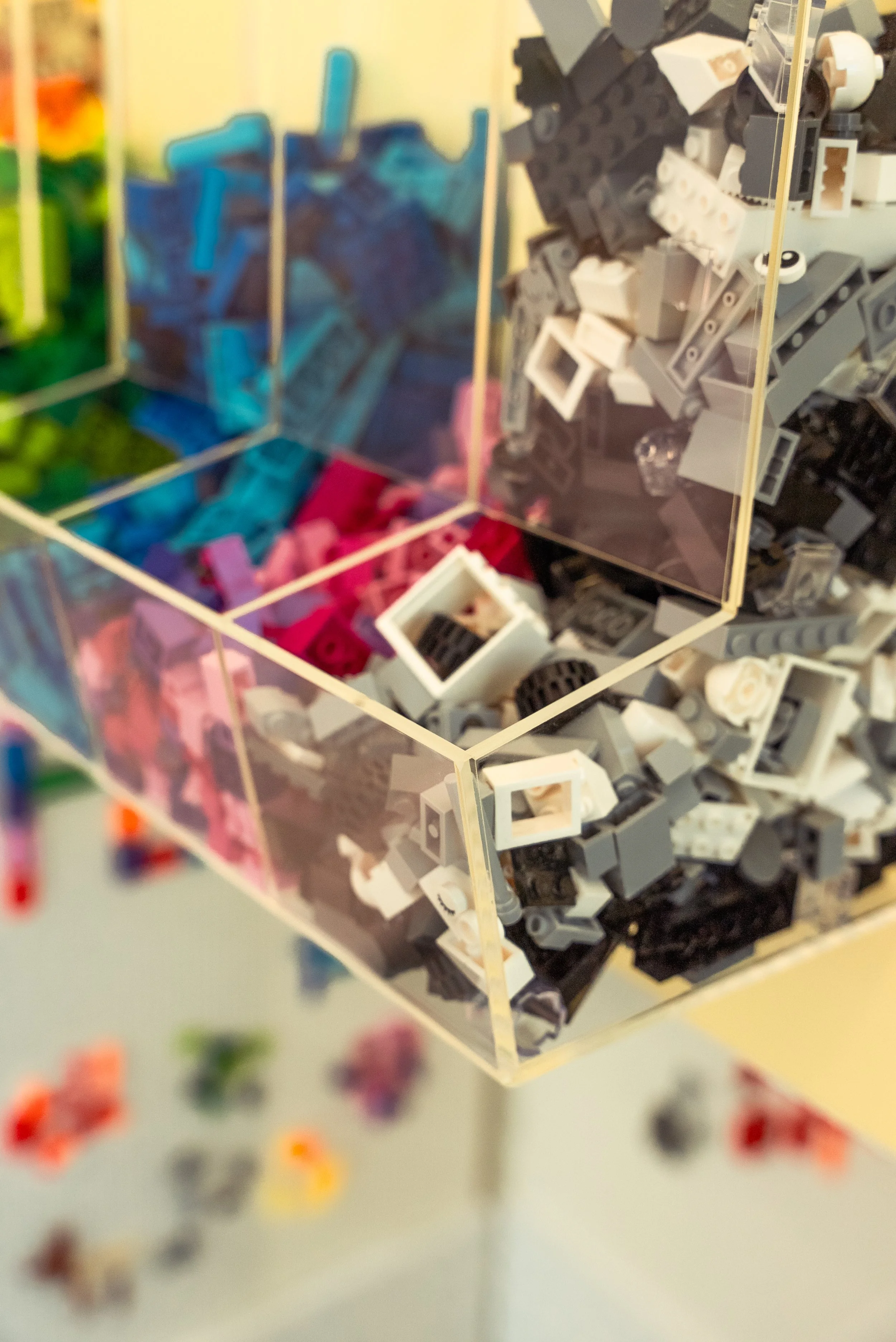 Clear acrylic display case with various small LEGO bricks and miniature pieces sorted by color.