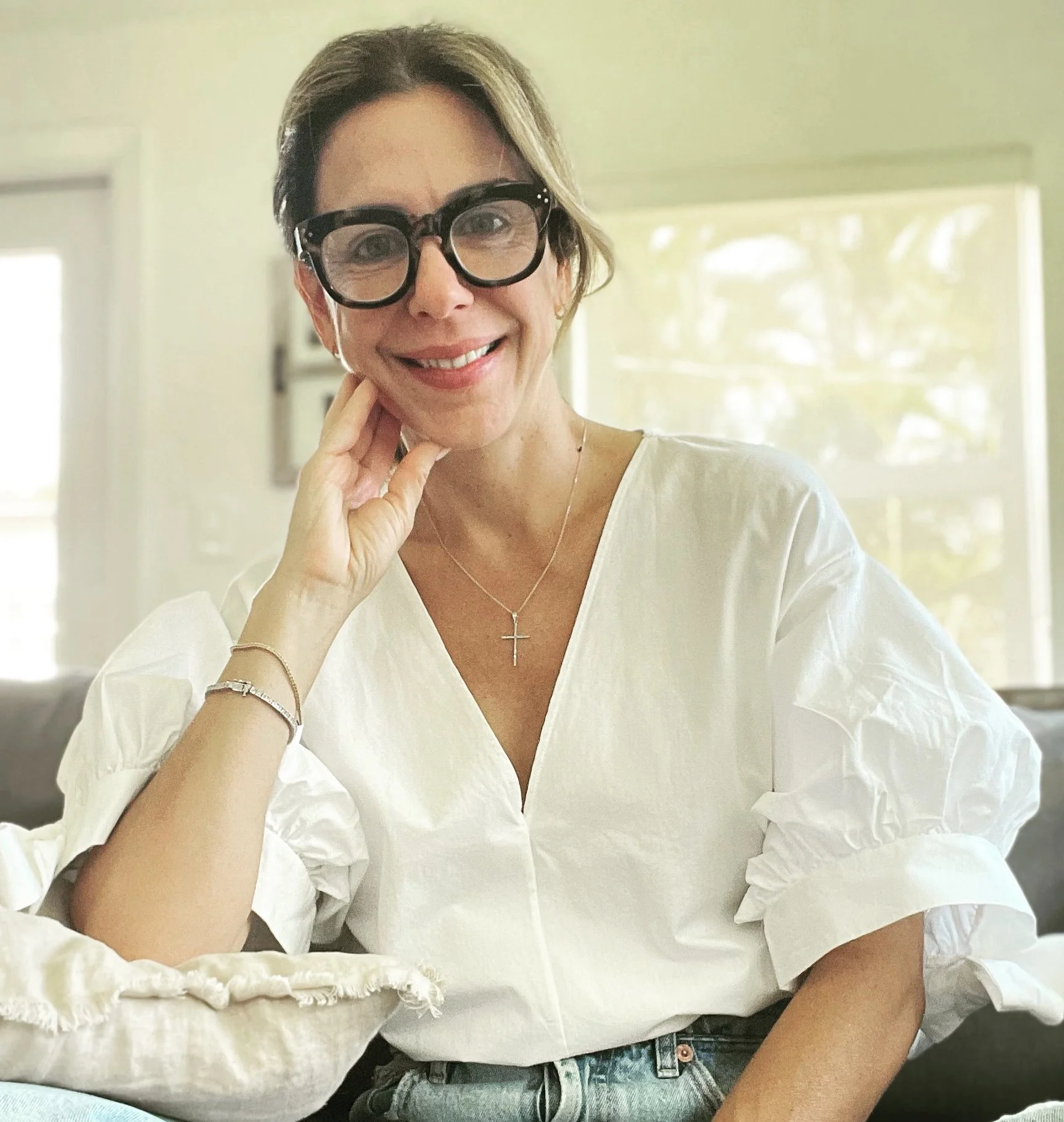 A smiling woman with glasses and white blouse