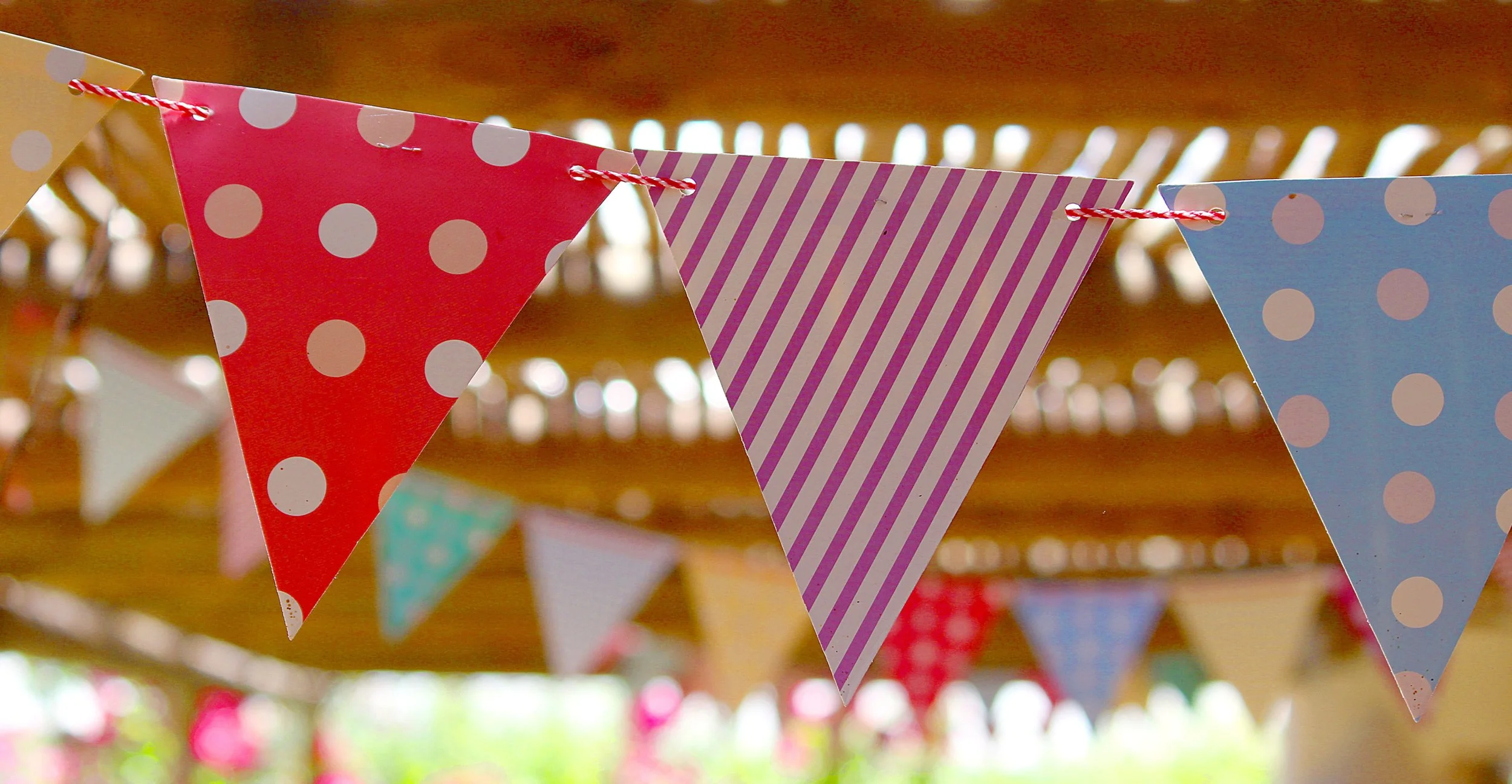 Close-up of decorative paper banners with polka dots and stripes hanging on a string.