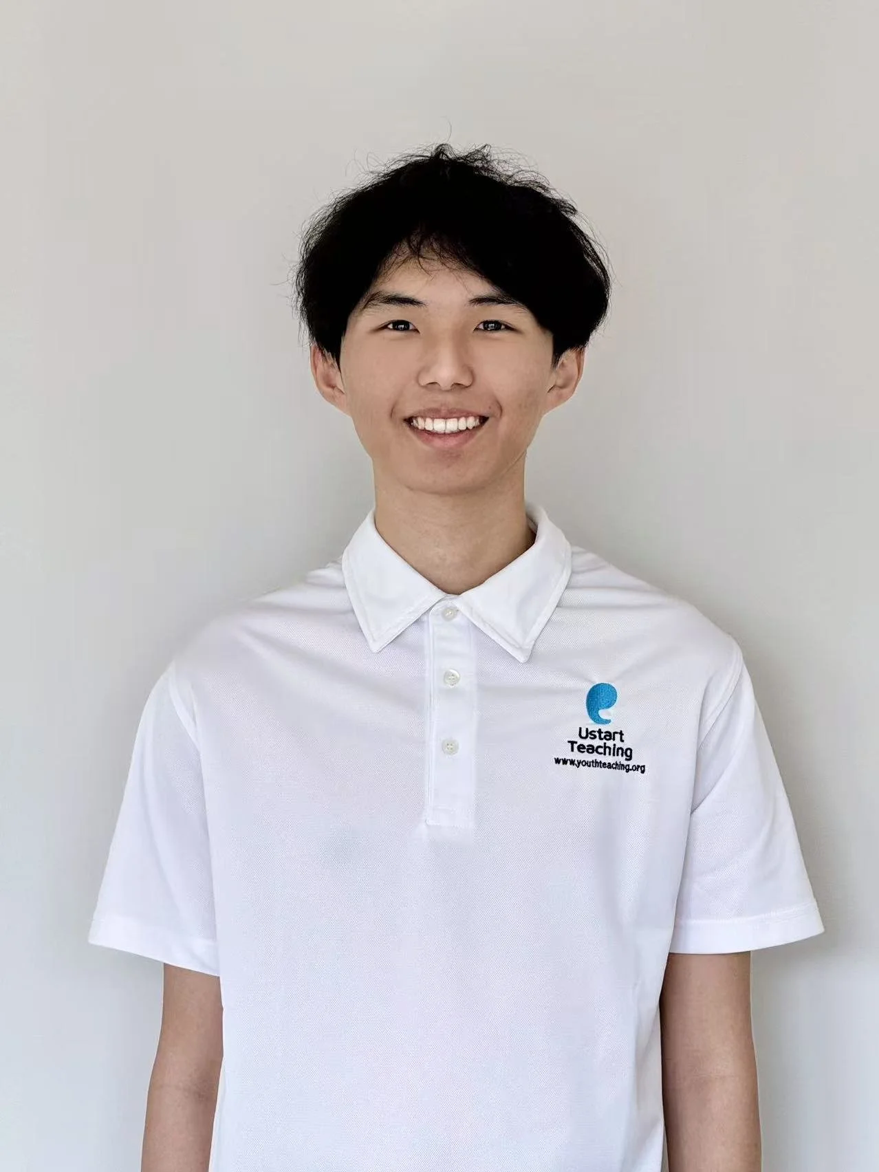 A young person with short, dark hair wearing a white polo shirt with a logo that says 'Ustar' on the chest, standing against a plain background.