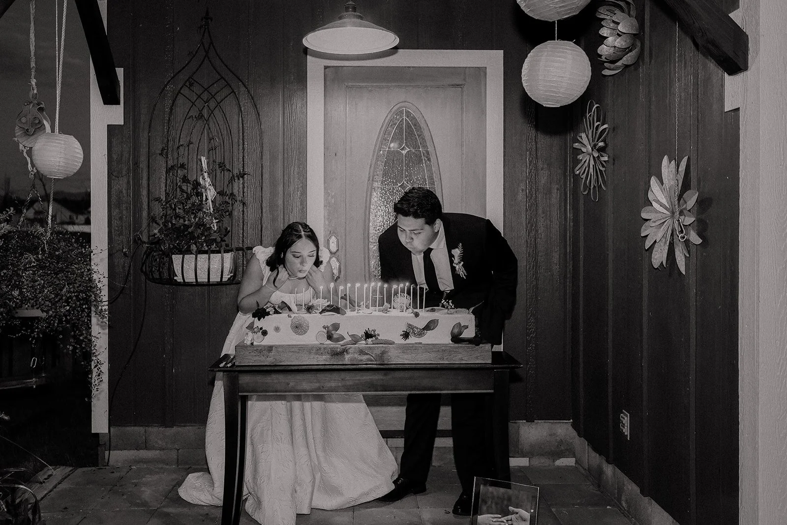 Photograph of a bride and groom in front of their wedding cake in Syracuse Utah