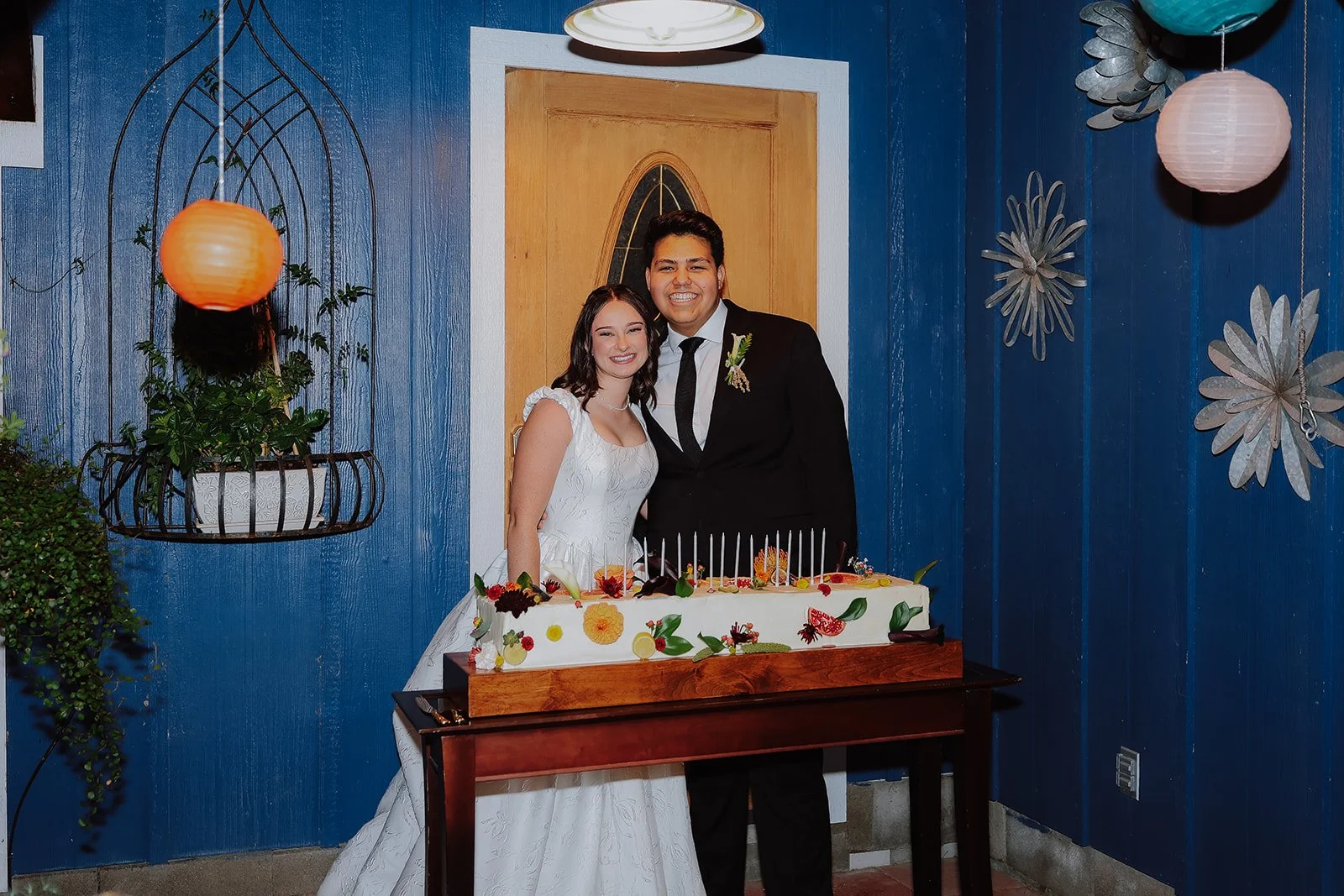 Photograph of a bride and groom in front of their wedding cake in Syracuse Utah