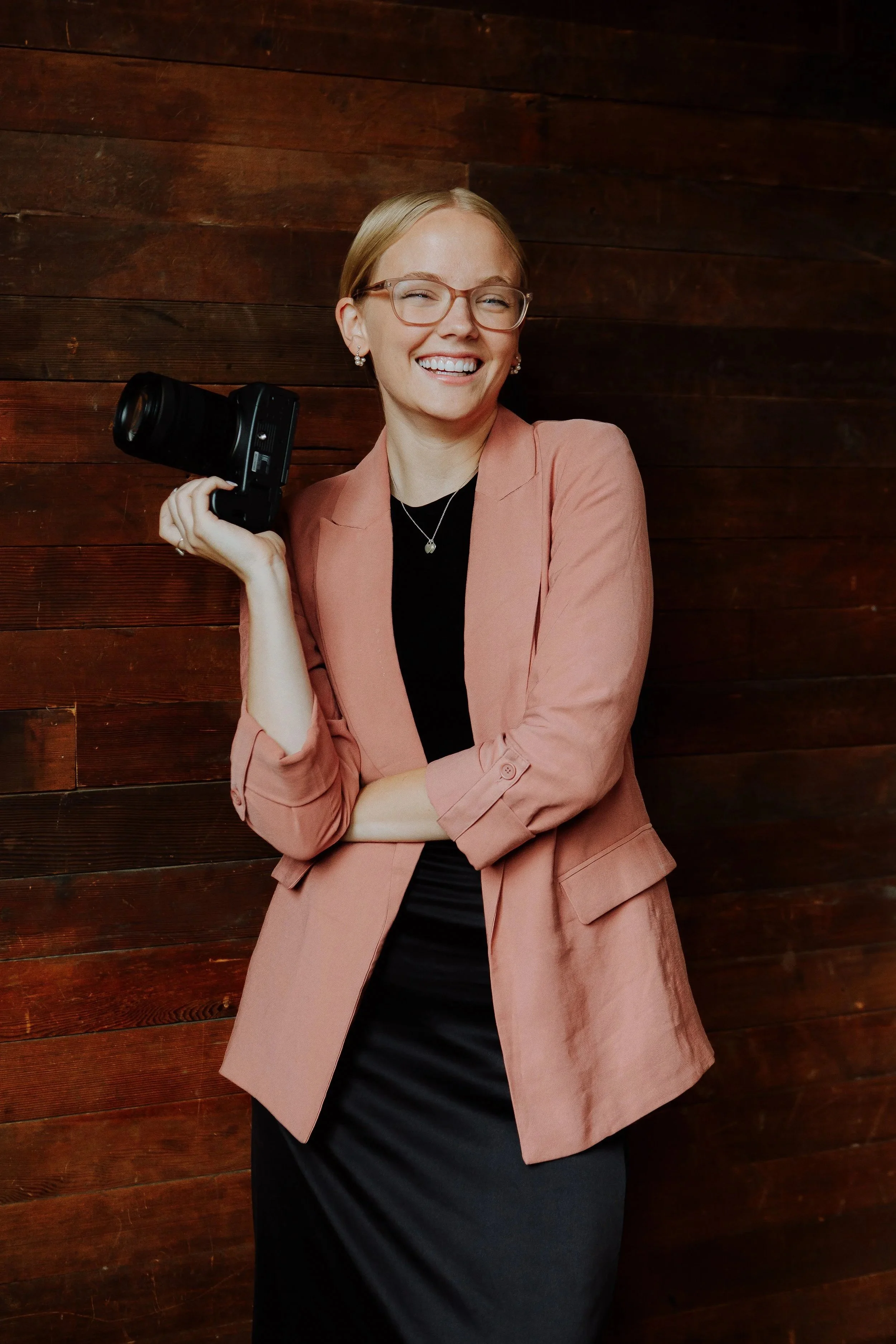 Photograph of Utah wedding photographer in a pink blazer with her camera