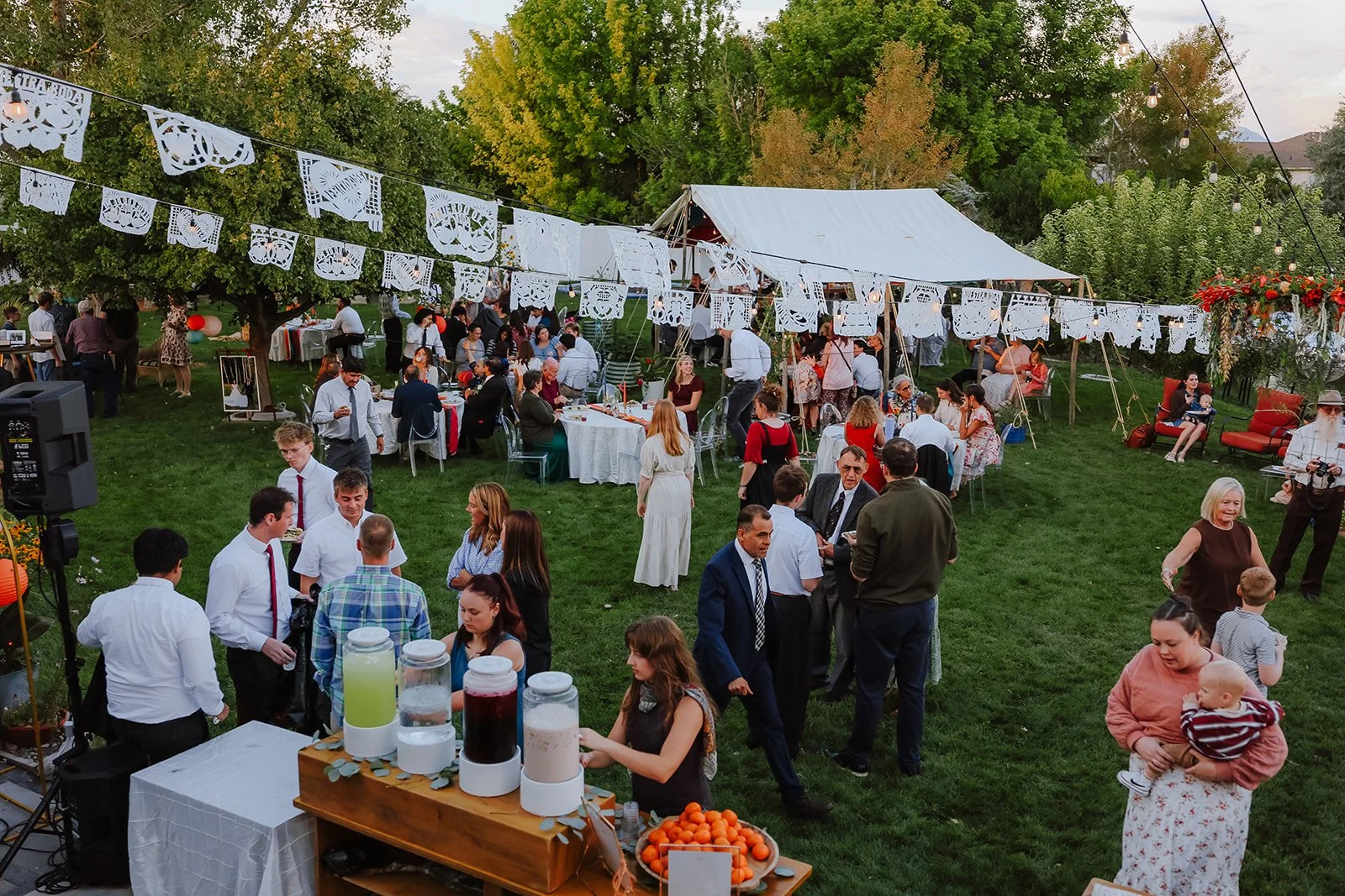 Photograph of a bride and groom in front of colorful decor for their backyard wedding reception syracuse, utah