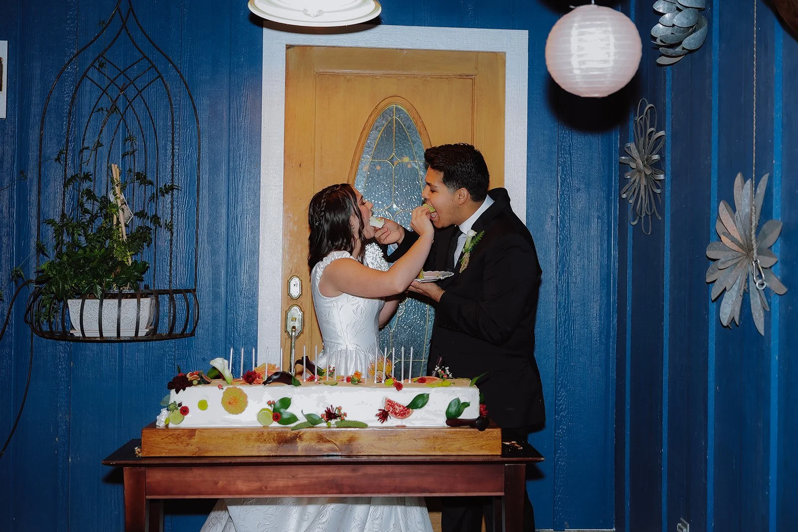 Photograph of a bride and groom in front of their wedding cake in Syracuse Utah