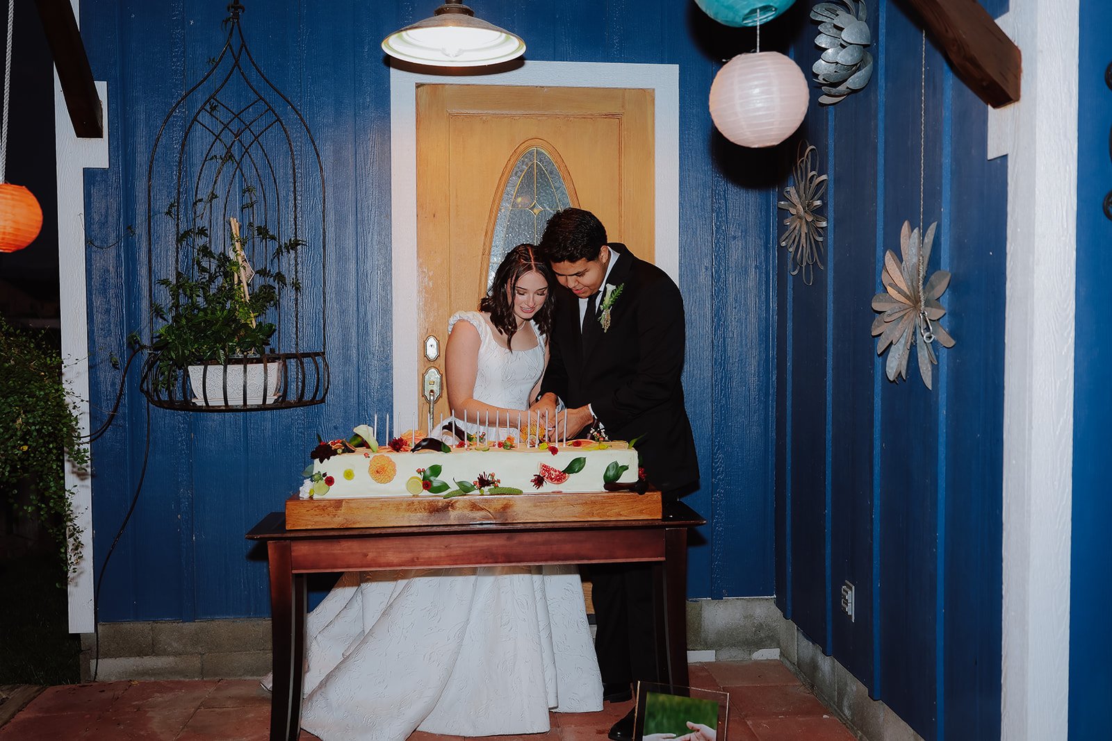 Photograph of a bride and groom in front of their wedding cake in Syracuse Utah