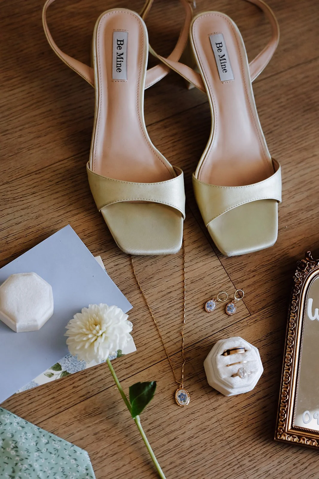 Photograph of a wedding flatlay with wedding ring, ties, and shoes 