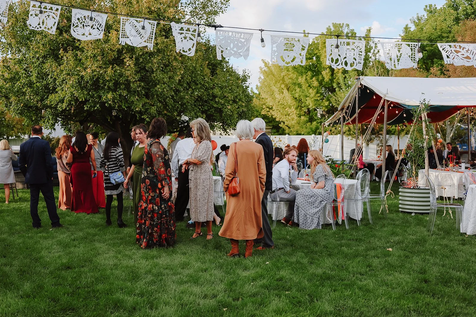 Photograph of a bride and groom in front of colorful decor for their backyard wedding reception