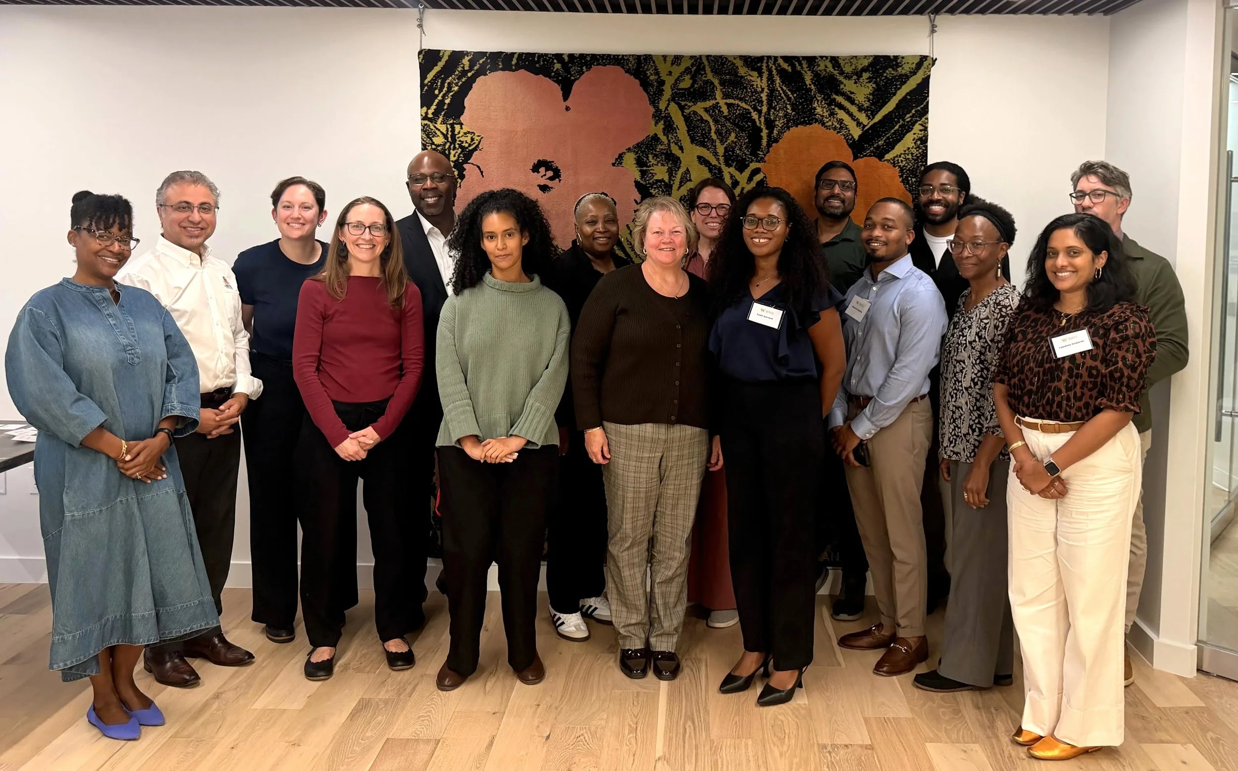Attendees of the Washington Area Women’s Foundation’s ECEFC convening stand, smiling at the camera, Kimberly Rusnak is fourth from the left, in a sark red shirt and Steffi Benjamin is third from the right in a patterned black and white shirt