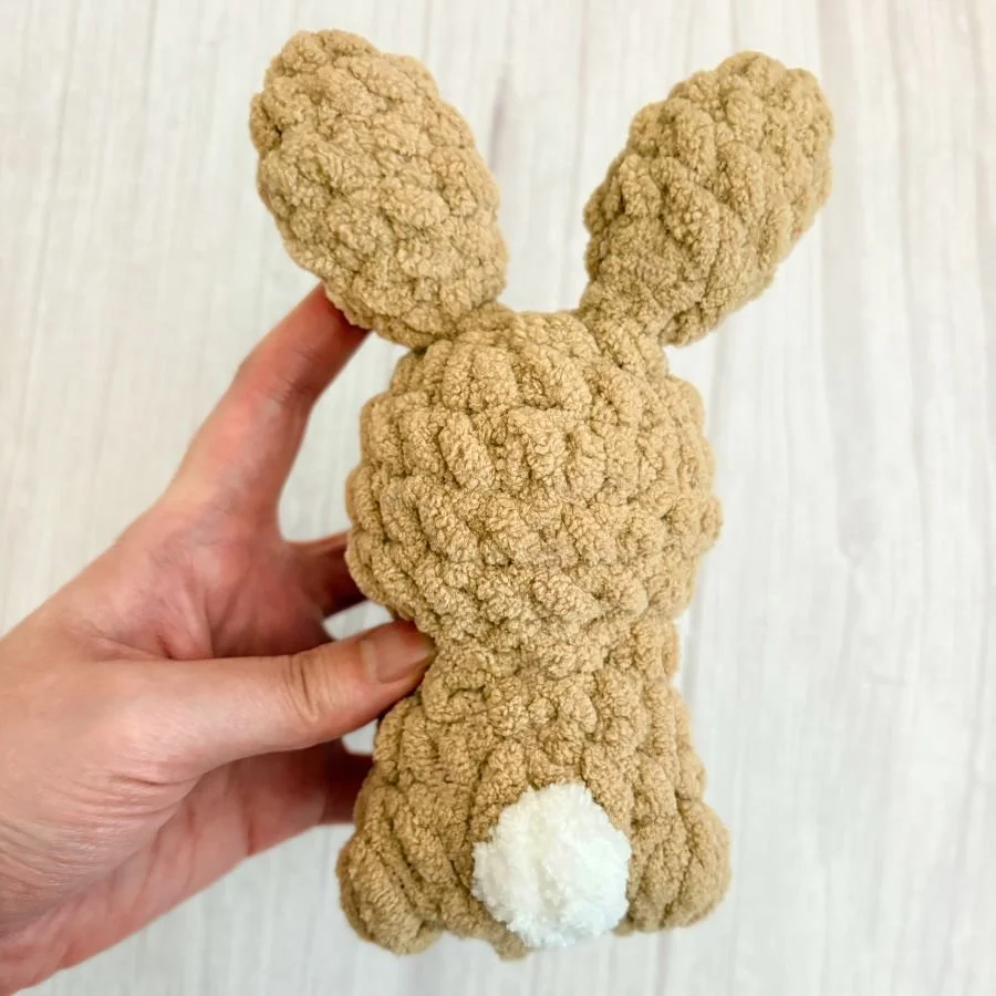 back view of a small crochet, brown rabbit with a white tail