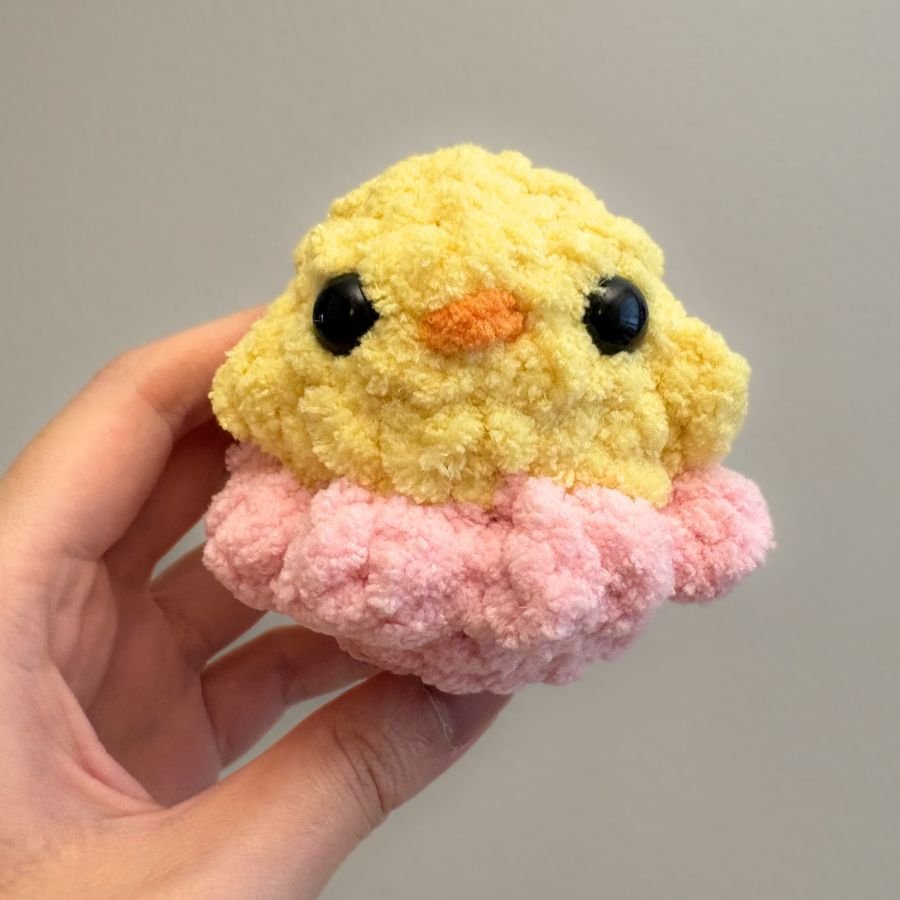 little crochet yellow chick sticking out of a pink crochet eggshell