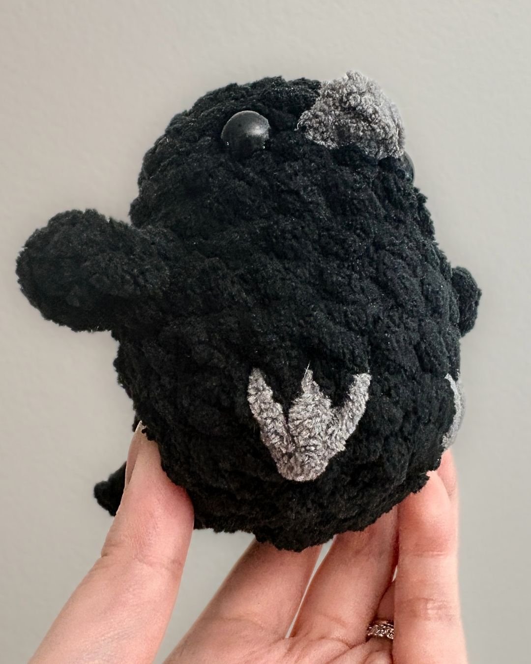 crochet raven from the bottom angle, showing a gray embroidered foot - free no sew crow amigurumi pattern