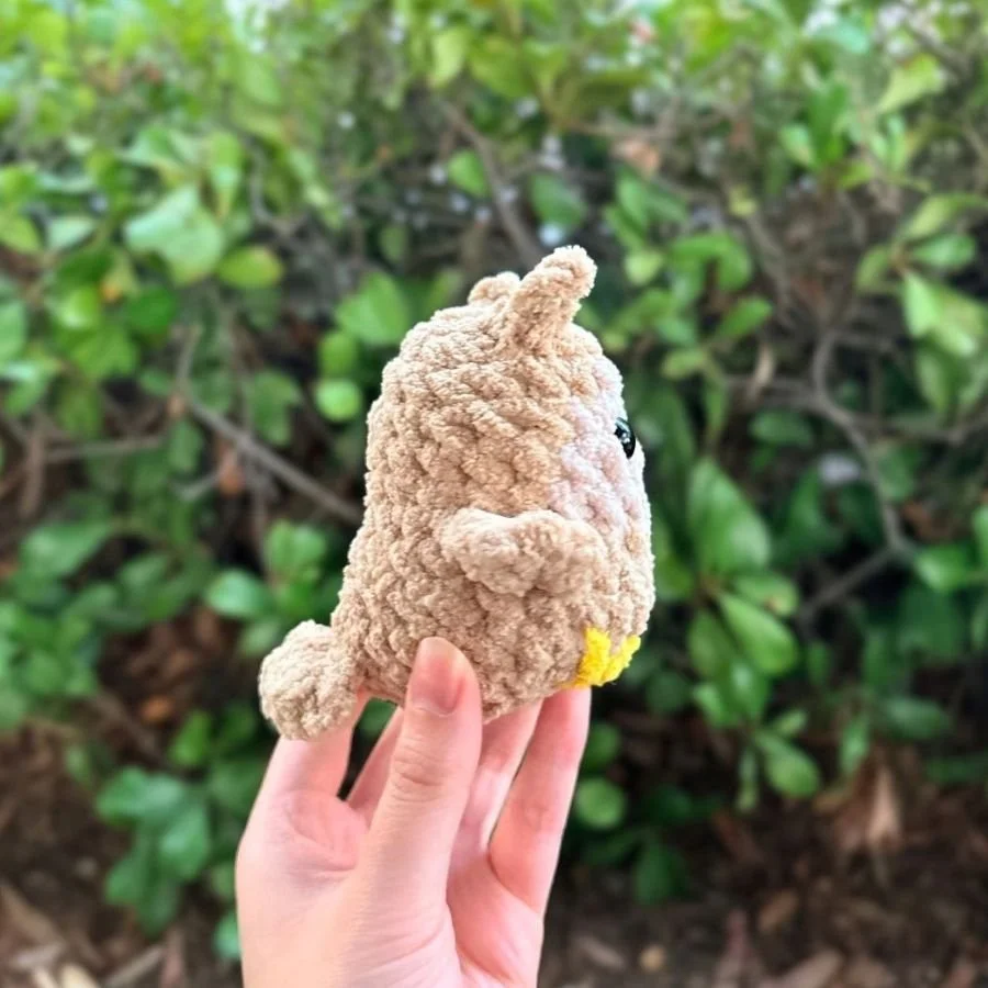 the side view of a little no-sew crochet owl made of brown, beige, and yellow yarn - free crochet owl pattern