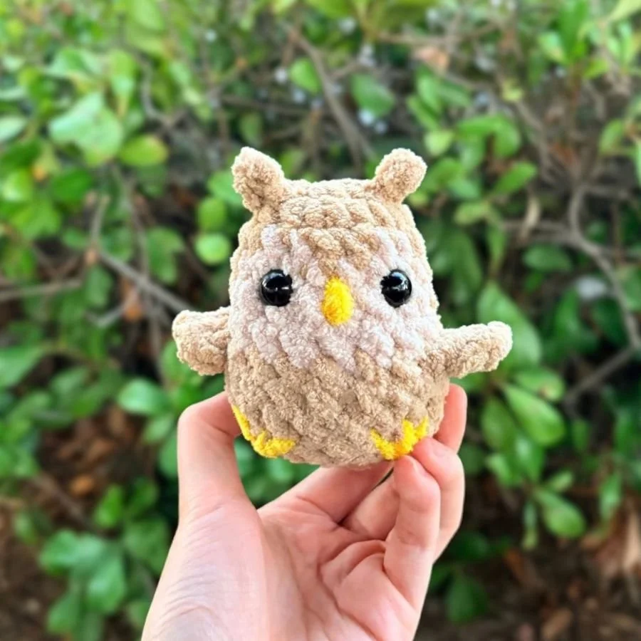 little amigurumi owl made with blanket yarn and held up by a hand - free amigurumi owl pattern