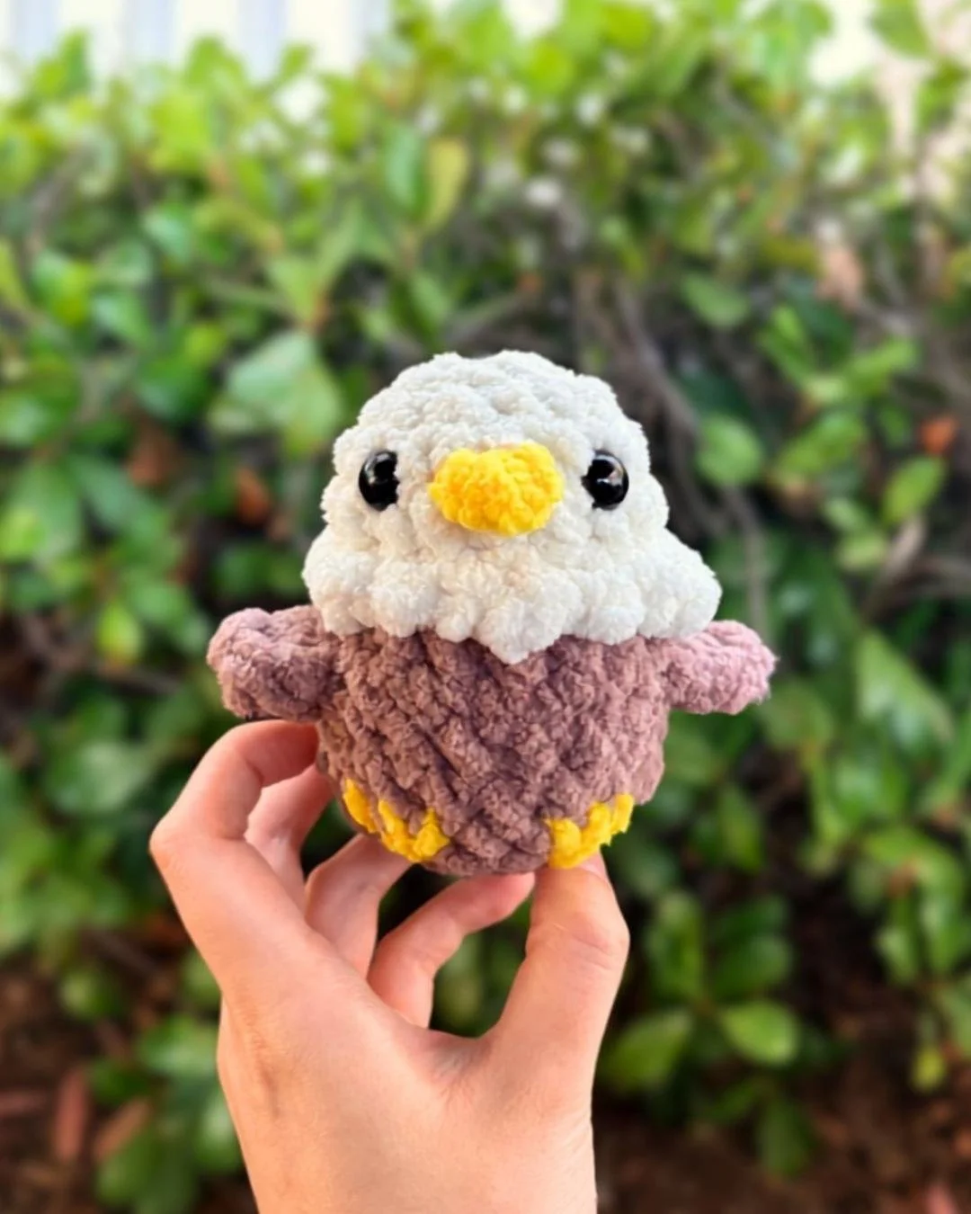 little crochet no sew bald eagle made with blanket yarn and held up in a hand - free crochet mini eagle amigurumi pattern