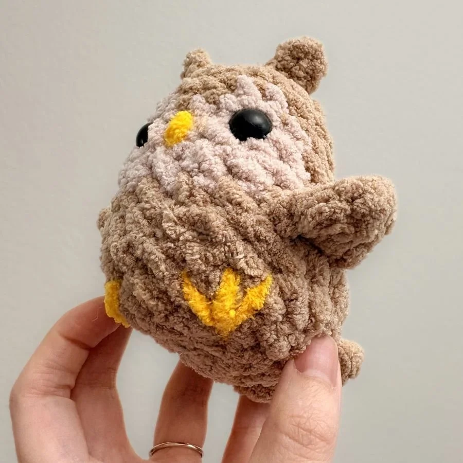 a bottom up angle view of the crochet owl to show the embroidered yellow foot