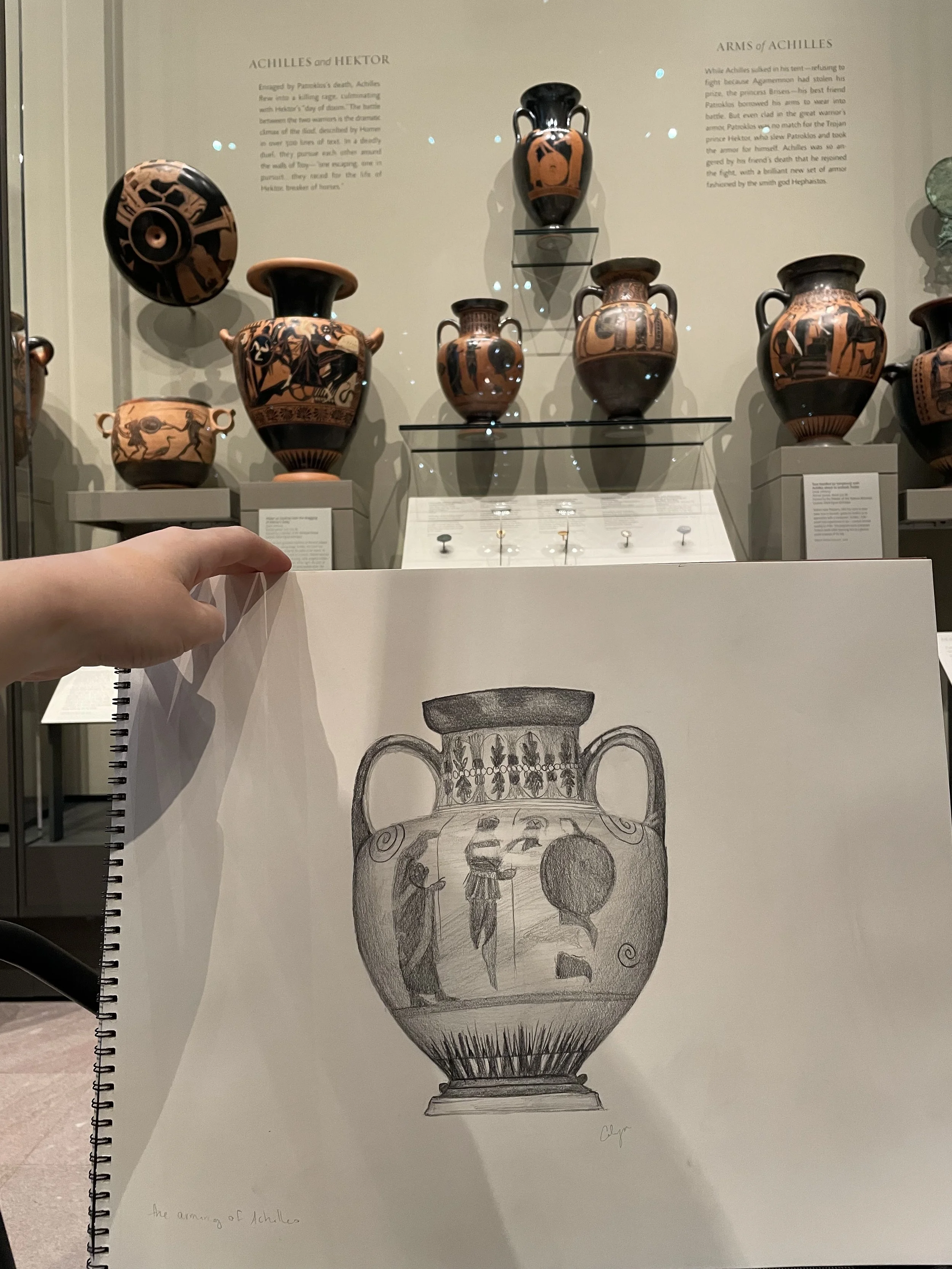Drawing of an ancient Greek vase with images of soldiers, horses, and weaponry, titled "The Armory of Achilles," signed by an artist named Lydia.