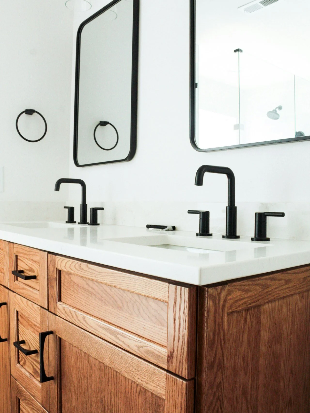 A double vanity blends natural wood cabinetry with crisp white surfaces and matte black fixtures for a look that feels both grounded and refined. 

Clean lines, thoughtful symmetry, and timeless materials make this Matthews renovation as functional a