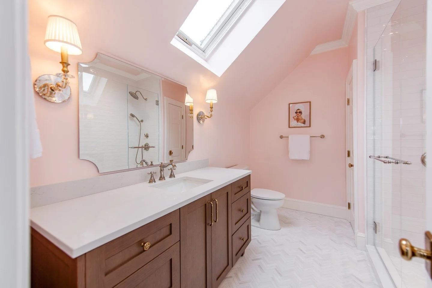 Blush walls, herringbone tile floors, and custom wood cabinetry come together in this thoughtfully designed bathroom renovation near Carmel Country Club. Warm brass fixtures, tailored millwork, and soft lighting create a timeless, elevated space that