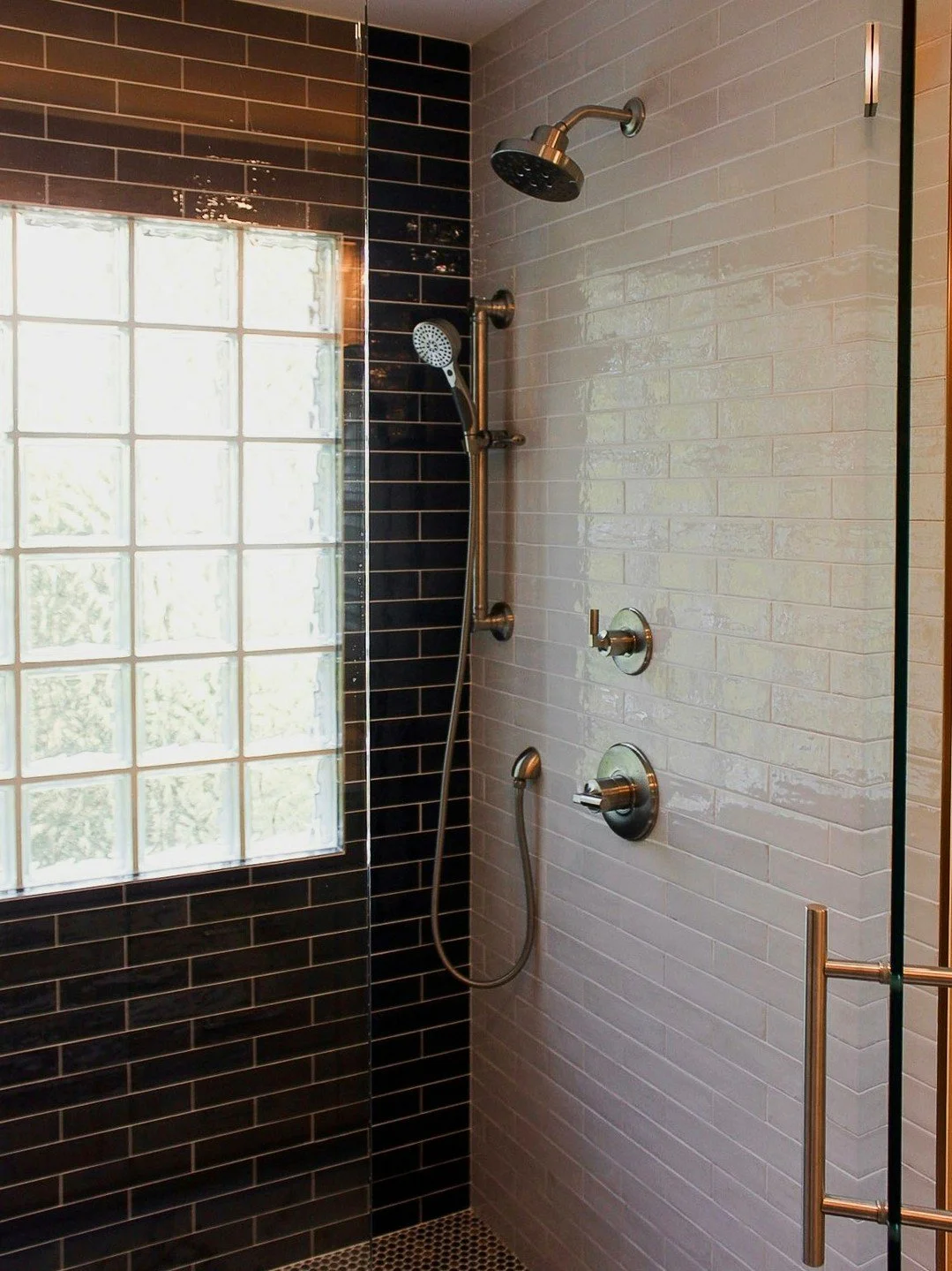 This Providence Planation bathroom renovation brings together crisp white subway tile, rich charcoal brick tile, and a multi-tone penny round mosaic that all meet in a single, intentional transition. The contrast in color and scale adds depth, while 