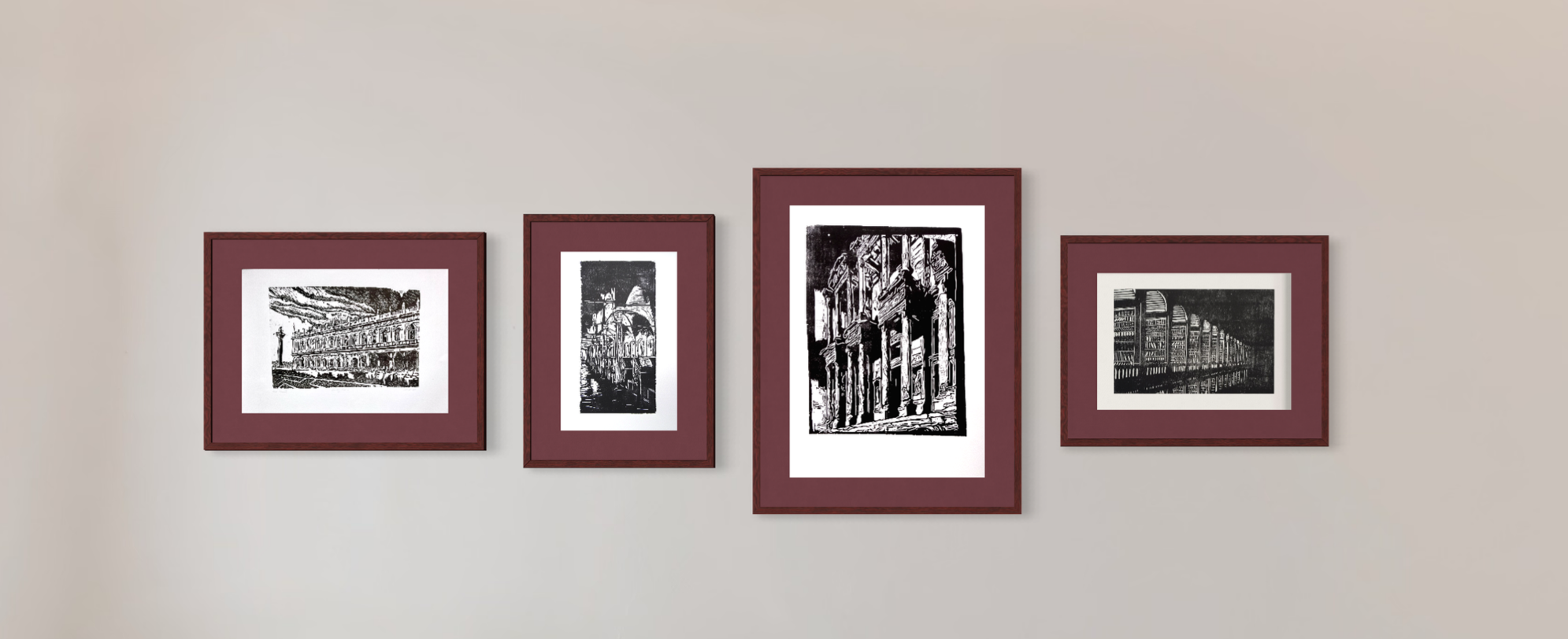 Four framed black and white artwork prints hanging on a beige wall.