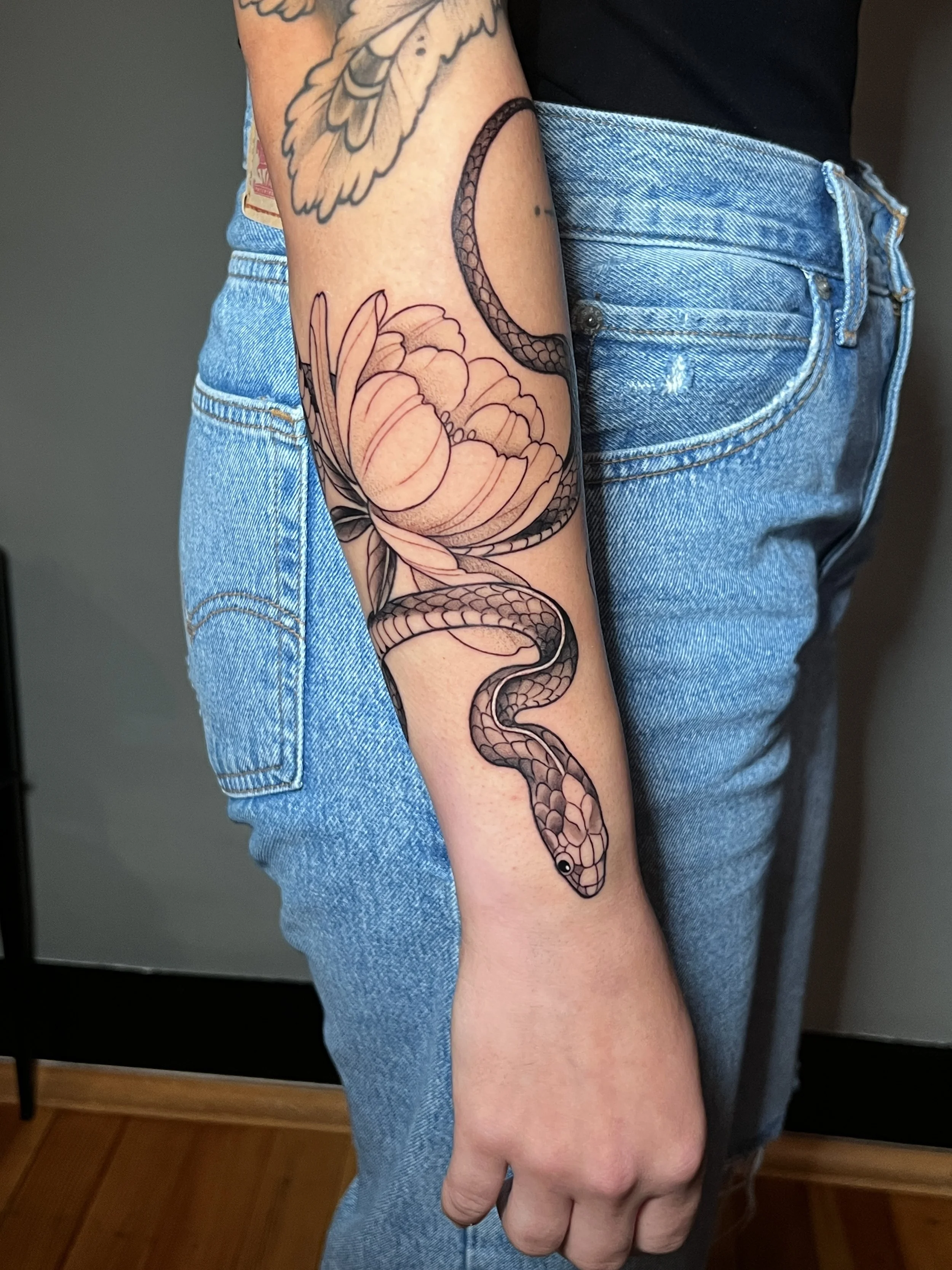Floral and snake arm wrap tattoo with high contrast and clean details, designed and tattooed by Maya Wild at Sub Rosa Tattoo Studio in Grants Pass, Oregon. This intricate piece highlights flow and complex details. Ideal for clients looking for delica