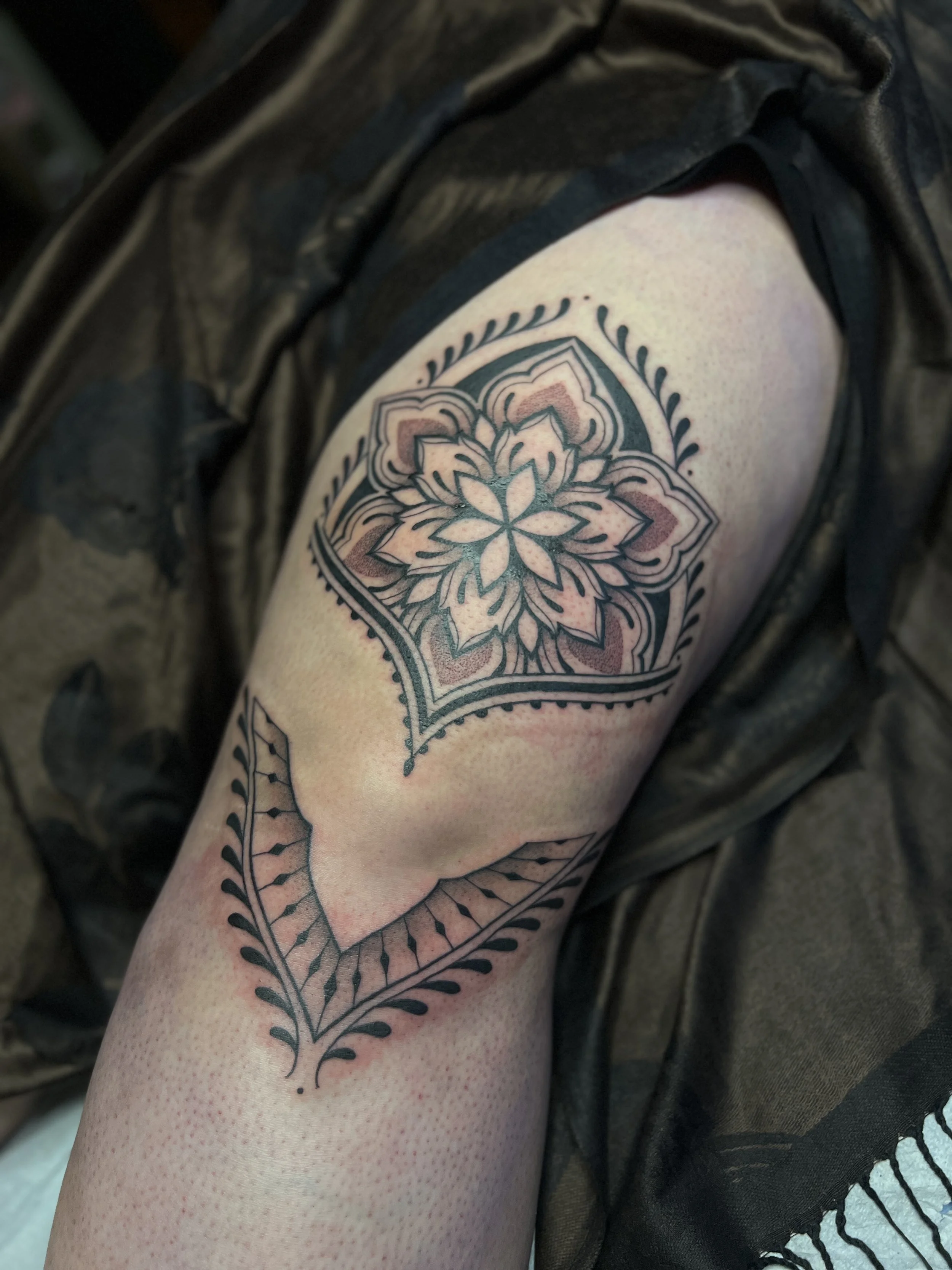 Bold ornamental thigh tattoo with thick lines and fine details, designed and tattooed by Maya Wild at Sub Rosa Tattoo Studio in Grants Pass, Oregon. This piece highlights symmetry and precision. Ideal for clients looking for bold yet feminine tattoo 