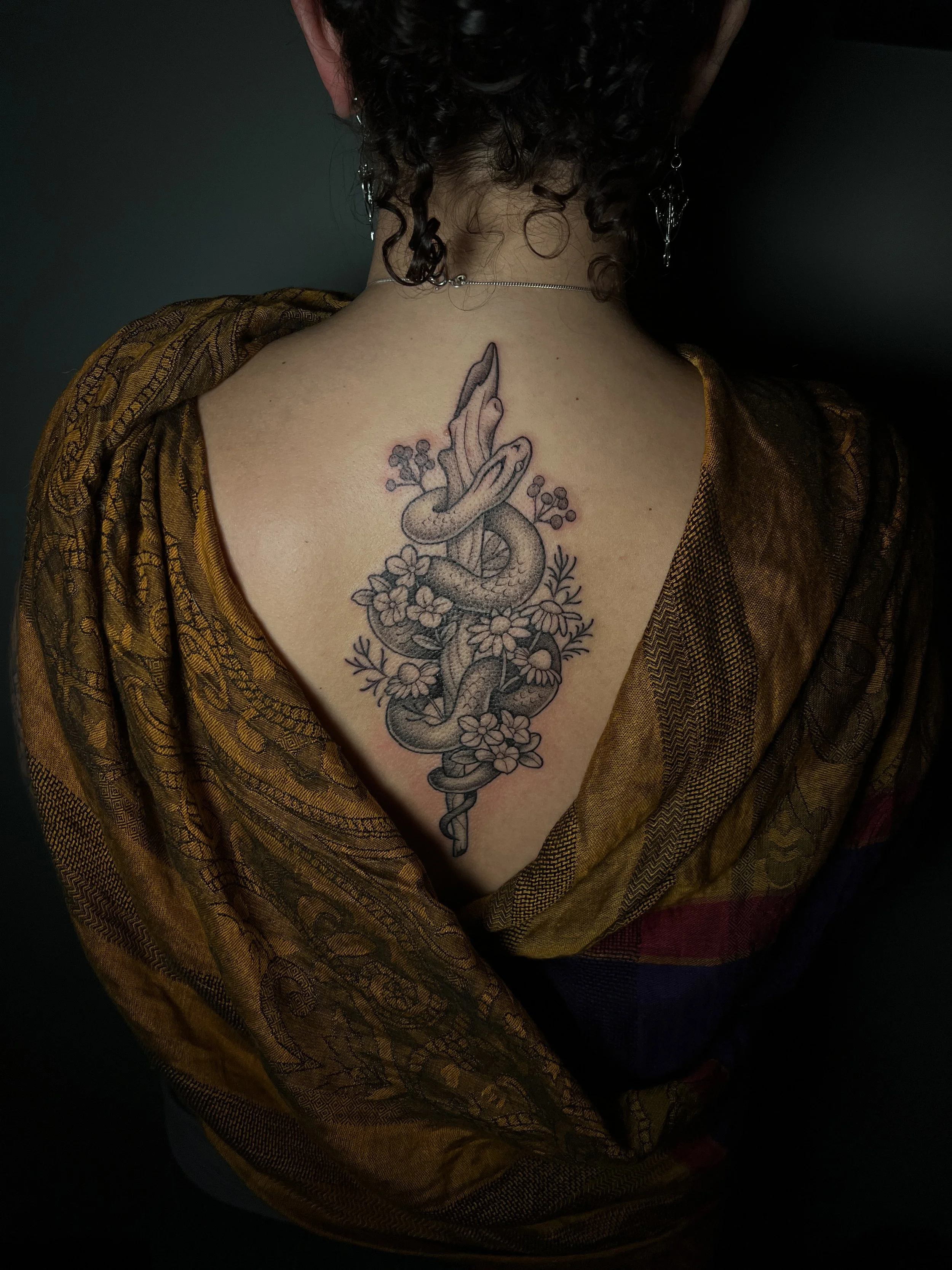 Illustrative Rod of Asclepius snake tattoo with botanical and healing flora elements, designed and tattooed by Maya Wild at Sub Rosa Tattoo Studio in Grants Pass, Oregon. This unique piece highlights sentimental meaning and intricate details. Ideal f