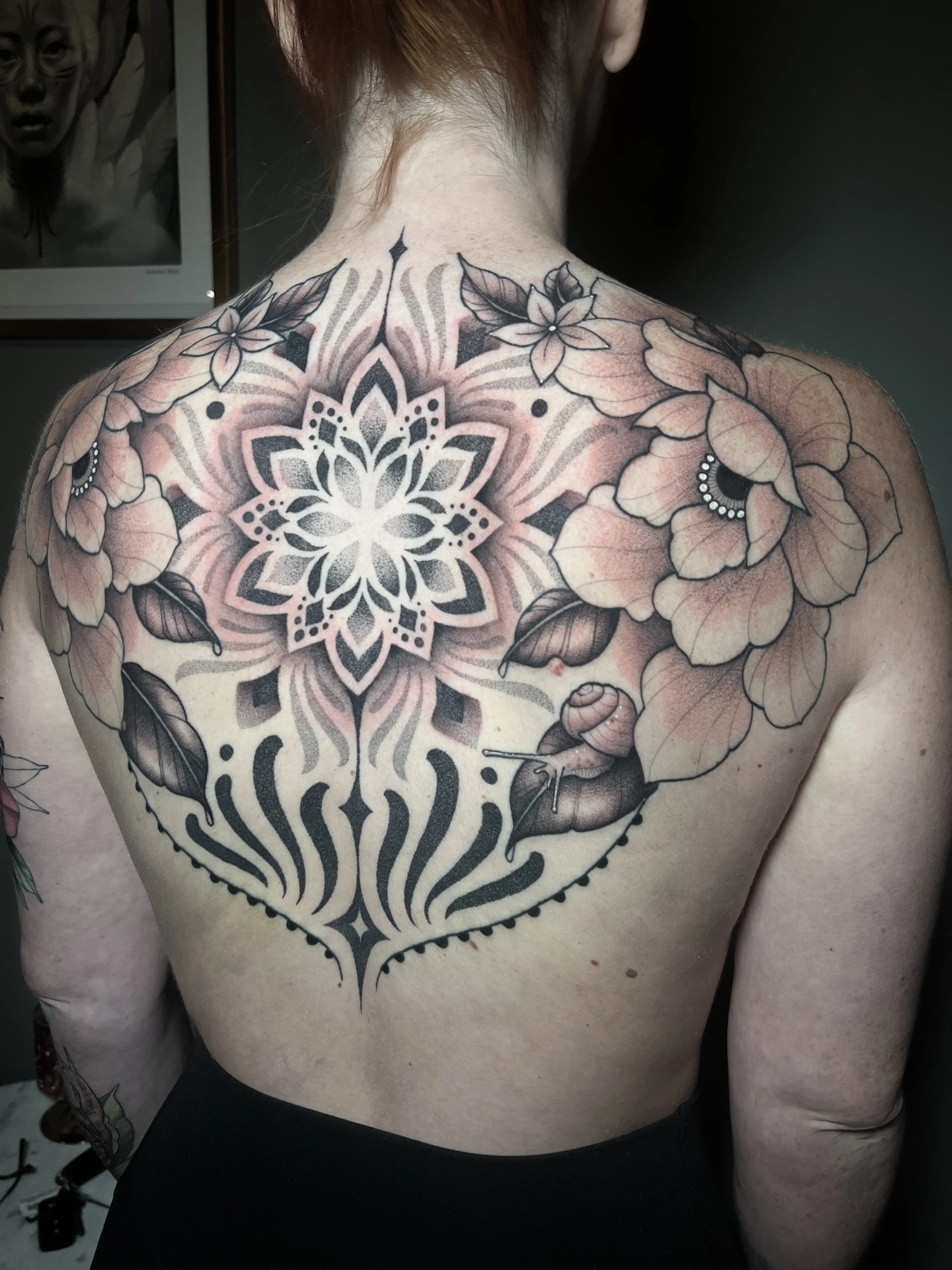 Floral mandala backpiece tattoo with dotwork and smooth shading, designed and tattooed by Maya Wild at Sub Rosa Tattoo Studio in Grants Pass, Oregon. This intricate piece highlights symmetry and complex details. Ideal for clients looking for feminine
