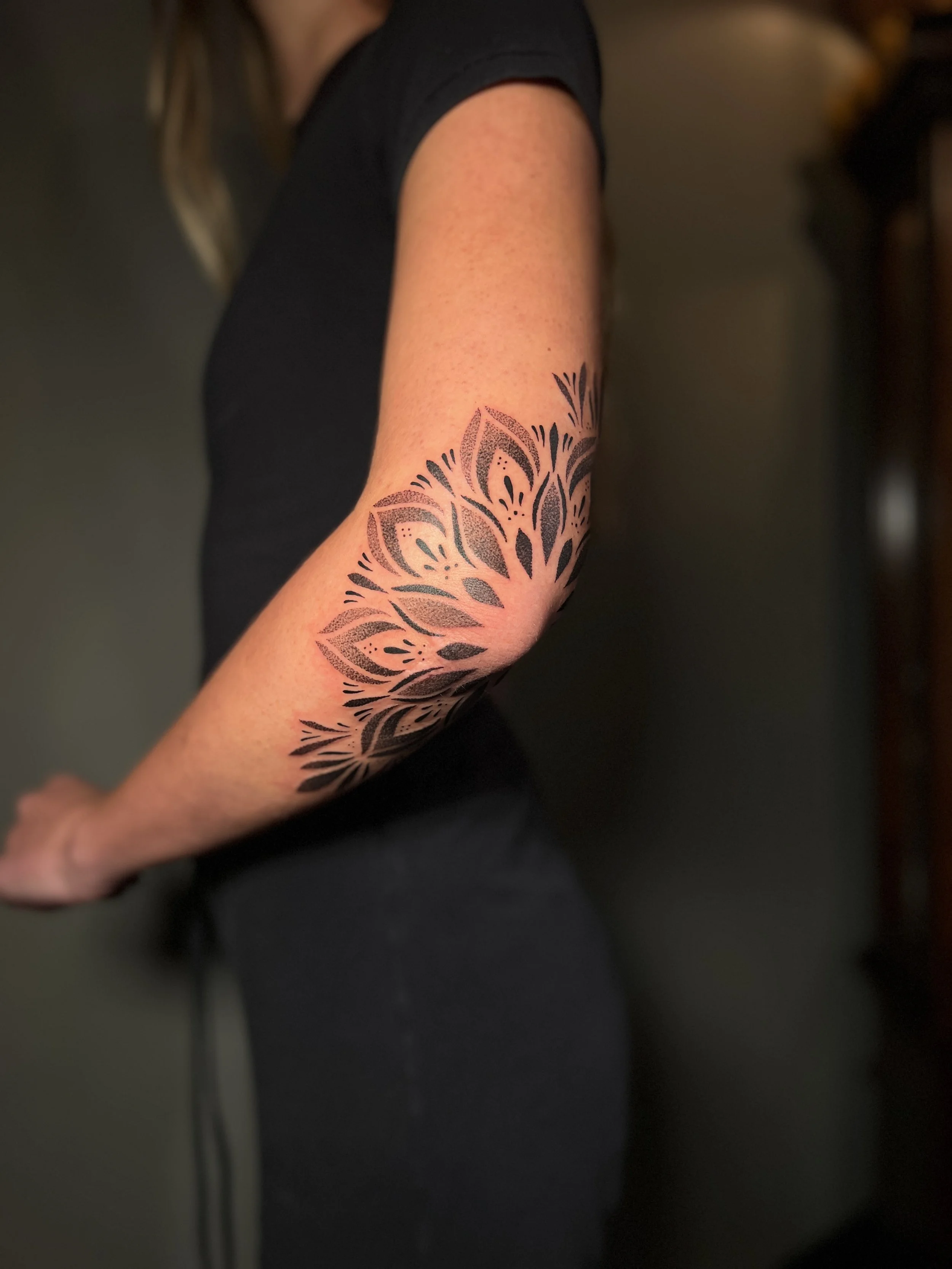 Ornamental mandala elbow tattoo with soft details, designed and tattooed by Maya Wild at Sub Rosa Tattoo Studio in Grants Pass, Oregon. This intricate piece highlights symmetry and floral elements to flatter the arm. Ideal for clients looking for fem